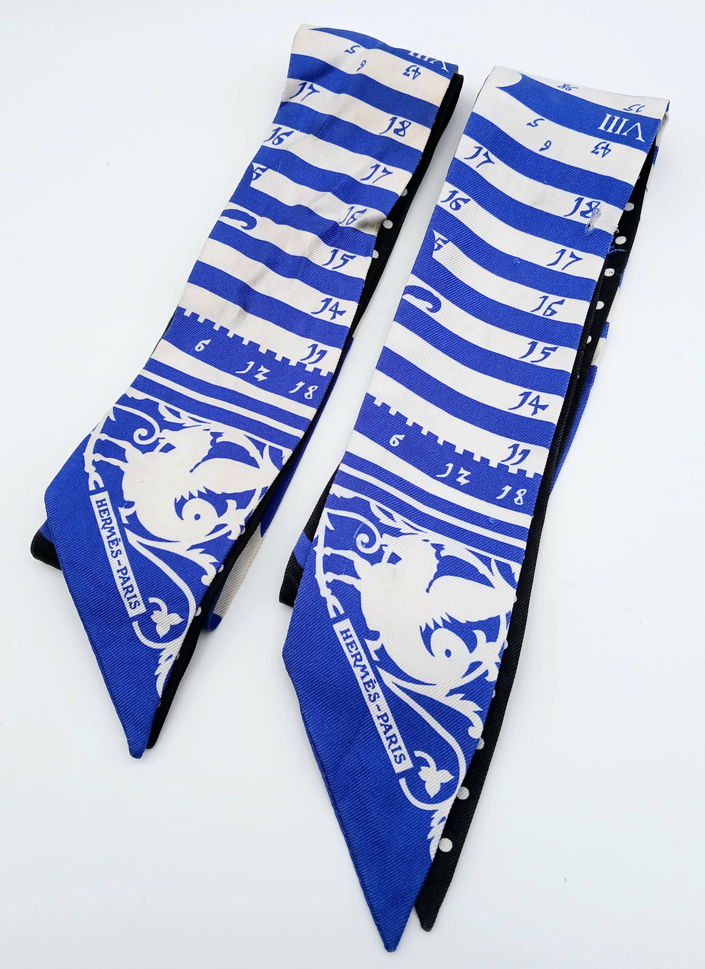 An Hermès “Astrologie à Pois” Twilly Silk Scarf.Blue and black silk with mixed astrology and polka dot motifs. Approximate size: 84.5cm x 5.2cm. Some light stains - Please see photos or request a condition report. Ref: 27843