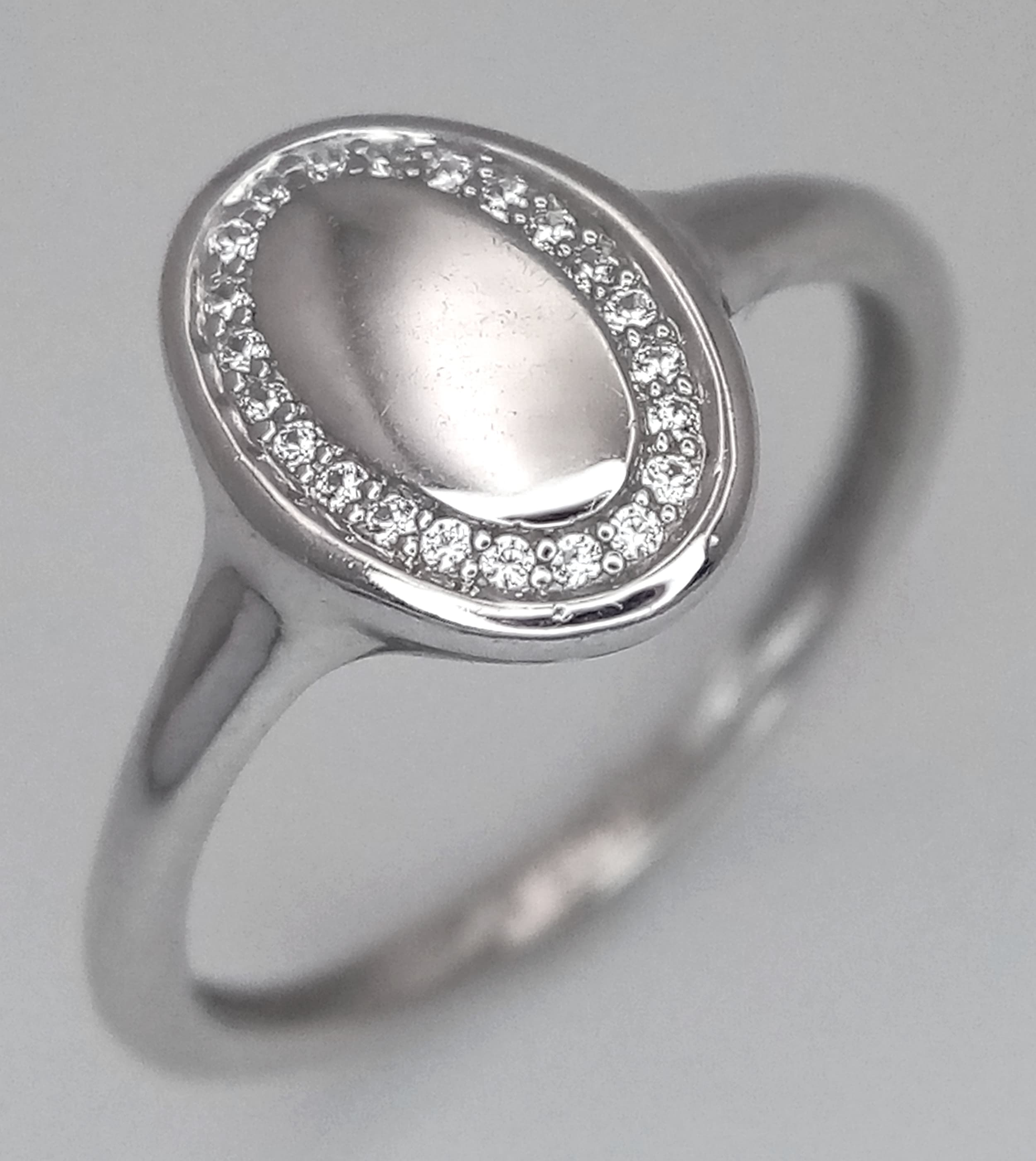 A 9K WHITE GOLD, DIAMOND SET, OVAL SHAPED, SIGNET STYLE RING. TOTAL WEIGHT 1.3G, SIZE G. SC 9028