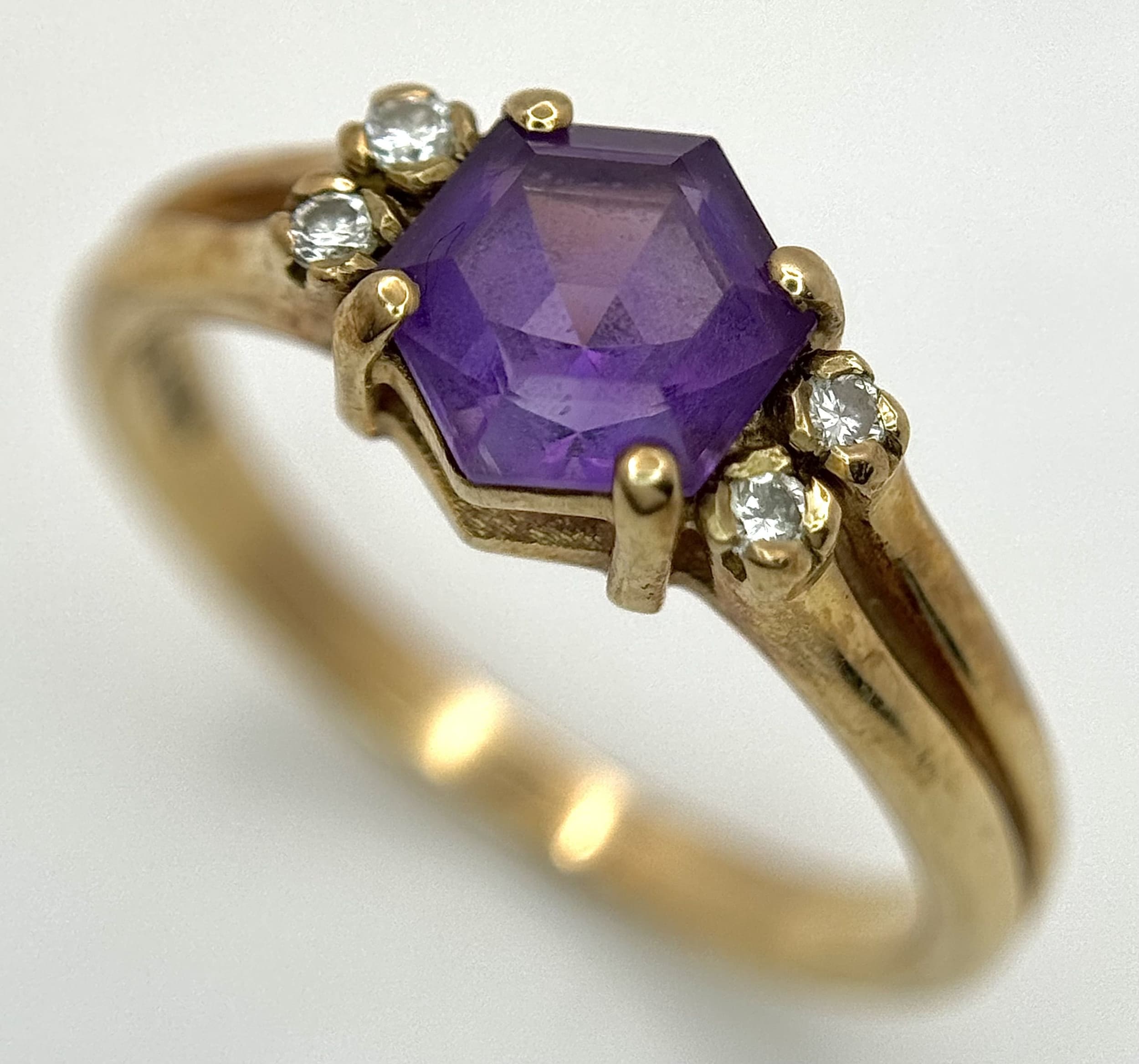 A 9K Yellow Gold Amethyst and Diamond Ring. Hexagonal centre cut amethyst with diamond accents. Size M. 2.93g total weight.