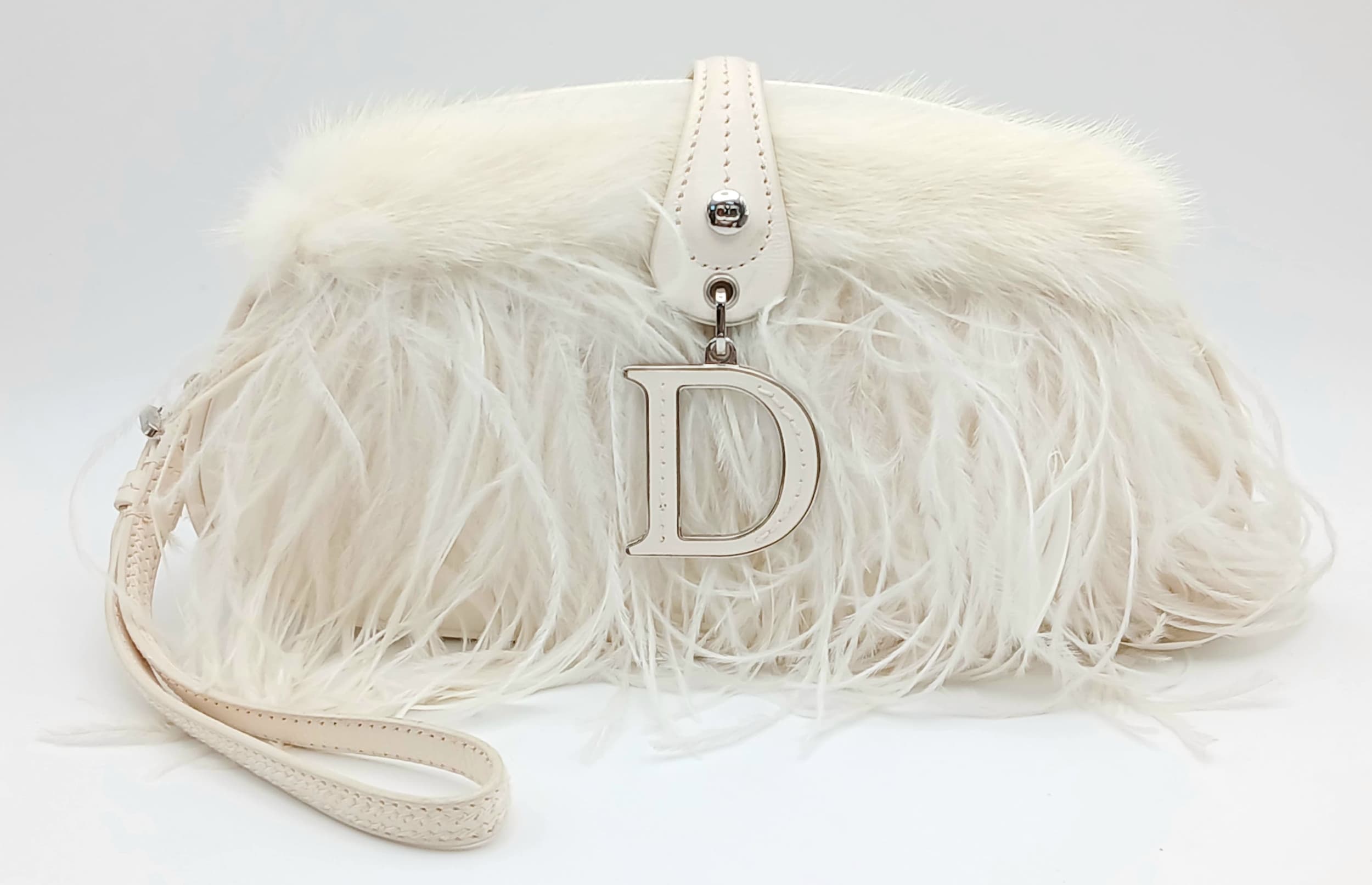 A Christian Dior White Satin and Feather Evening Clutch Bag. White satin exterior with layered feather detailing, silver-toned hardware, a wrist strap and magnetic flap closure. Grey Dior monogram textile interior with one main compartment and an open side pocket. Approx 22cm length x 10cm height x 5cm depth. Some marks and signs of wear to the leather. Comes with a COA, certificate of authenticity, care booklet and dust cover. Please see photos or request a condition report. Ref: 28648.