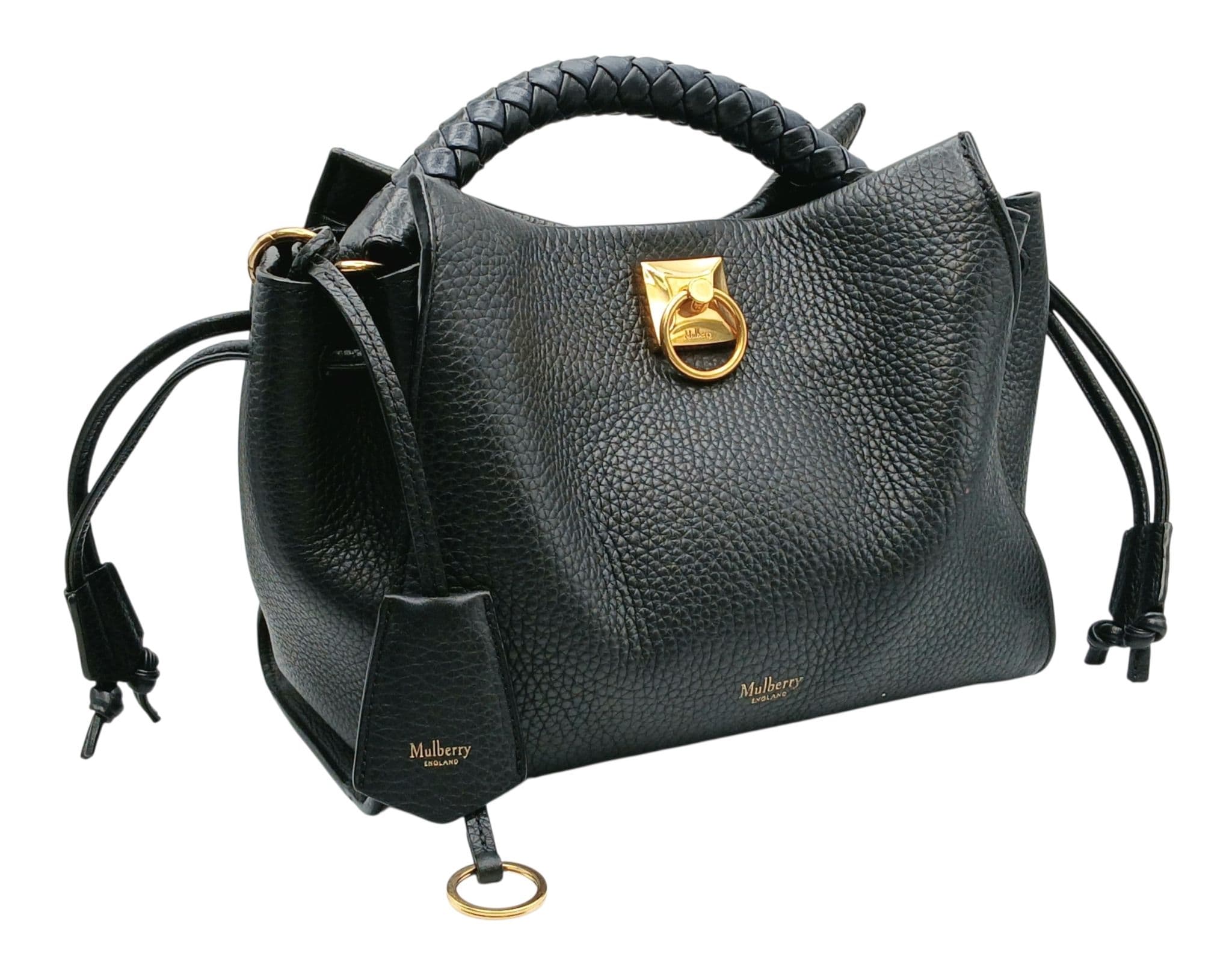 A Mulberry Black Grain Leather Small Iris Handbag. Black grained leather exterior with gold-toned hardware, braided top handle, detachable shoulder strap, drawstring side gussets and magnetic closure. Black textile interior with one main compartment and a zipped side pocket. Approx 25cm length x 19cm height x 13cm depth. Some scratches to the hardware and some signs of use but in good condition overall. Comes with a dust cover and care booklet. Please see photos or request a condition report. Ref: 28713.