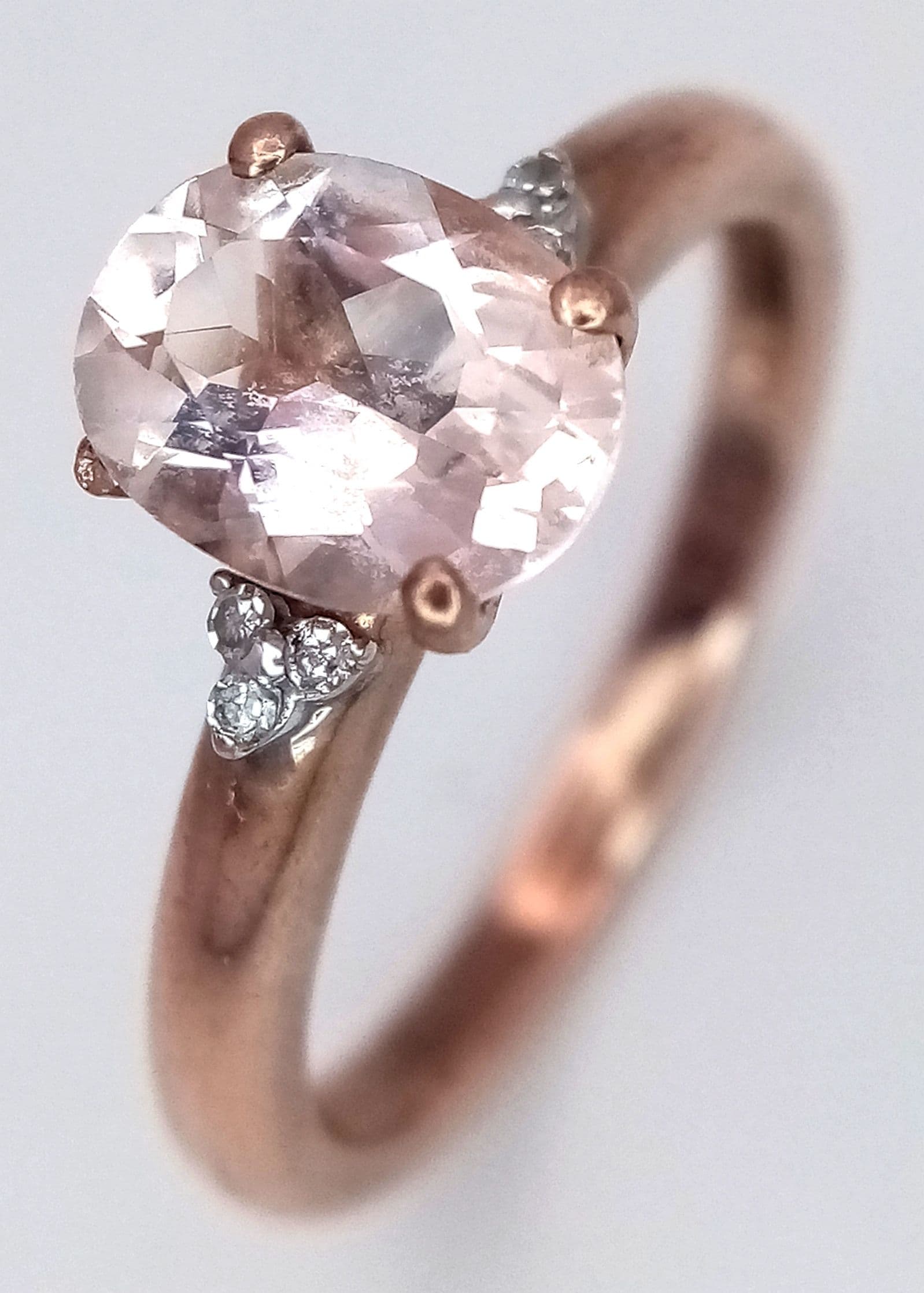 A VERY ATTRACTIVE 9K ROSE GOLD RING WITH WHITE FACETED CENTRE STONE FLANKED BY 6 SMALL DIAMONDS . 2.2gms size M