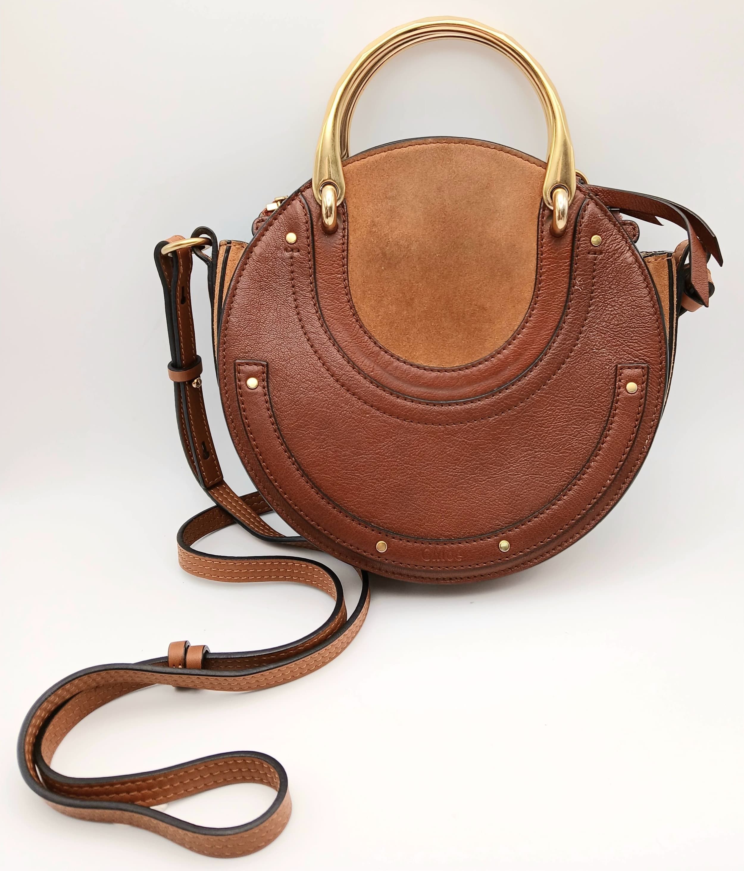 A Chloé Brown Leather and Suede Pixie Shoulder Bag. Brown grained leather exterior with gold-toned hardware, attachable shoulder strap and zipped top closure. Beige suede interior with one main compartment and an opened side pocket. Approx 20cm length x 20cm height x 5cm depth. Few tiny marks and signs of wear but in very good condition overall. Comes with a COA, care booklet and dust cover. Please see photos or request a condition report. Ref: 28640.