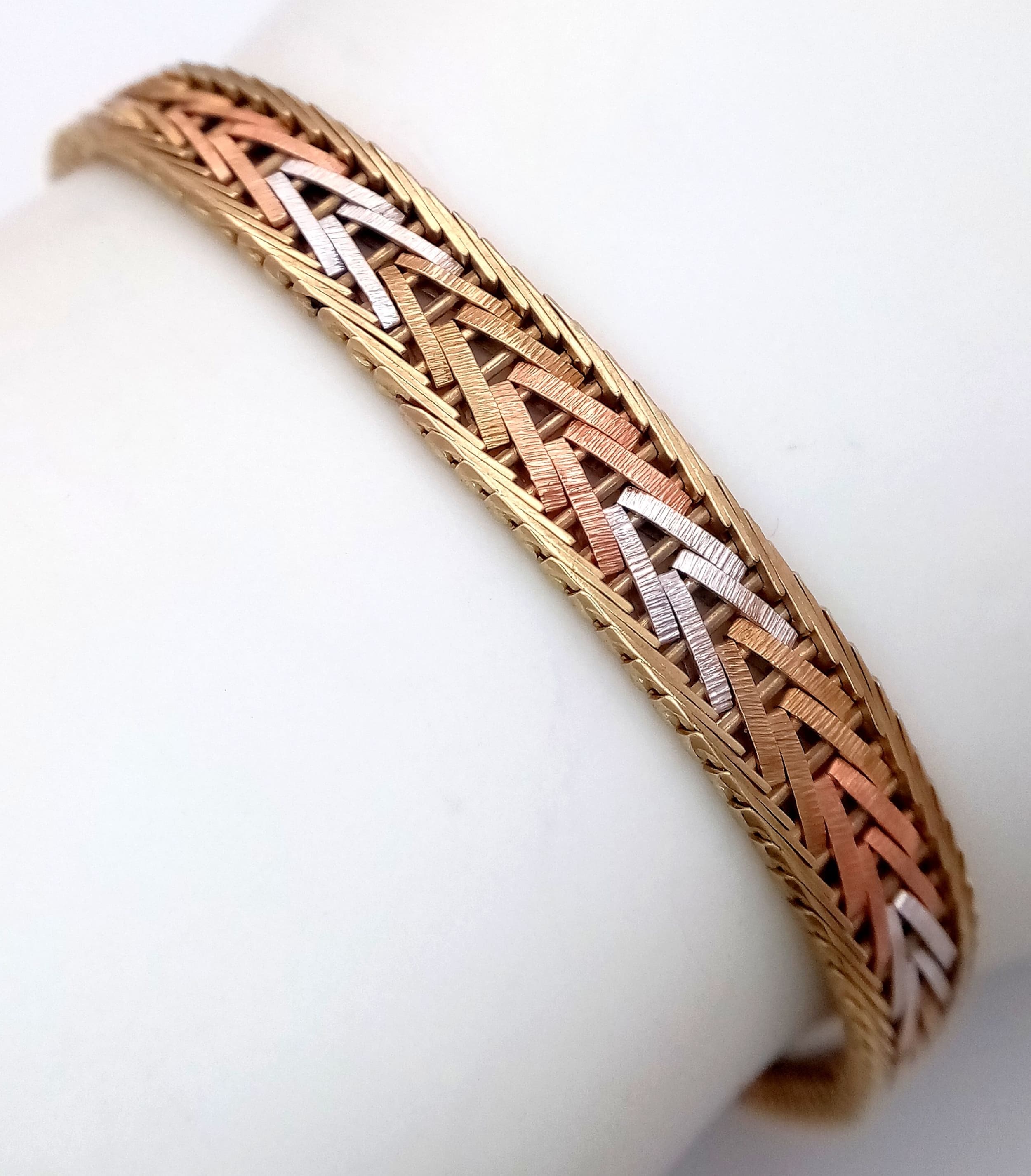 A 9K GOLD BRACELET WITH A CHEVRON DESIGN IN 3 COLOURED GOLD . 9gms