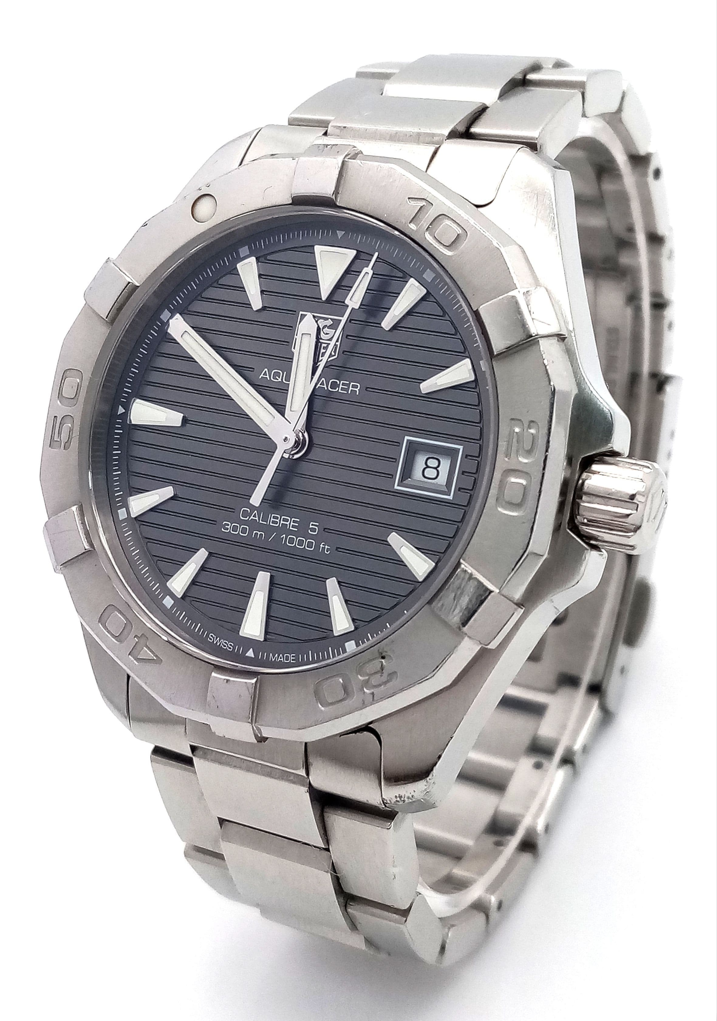 A Tag Heuer Aquaracer Calibre 5 Automatic Divers Watch. Water resistant to 300m. Stainless steel bracelet and case - 41mm. Black striped dial with date window. Rotating bezel. Comes with box, spare link and papers. In working order. Ref: 028602.