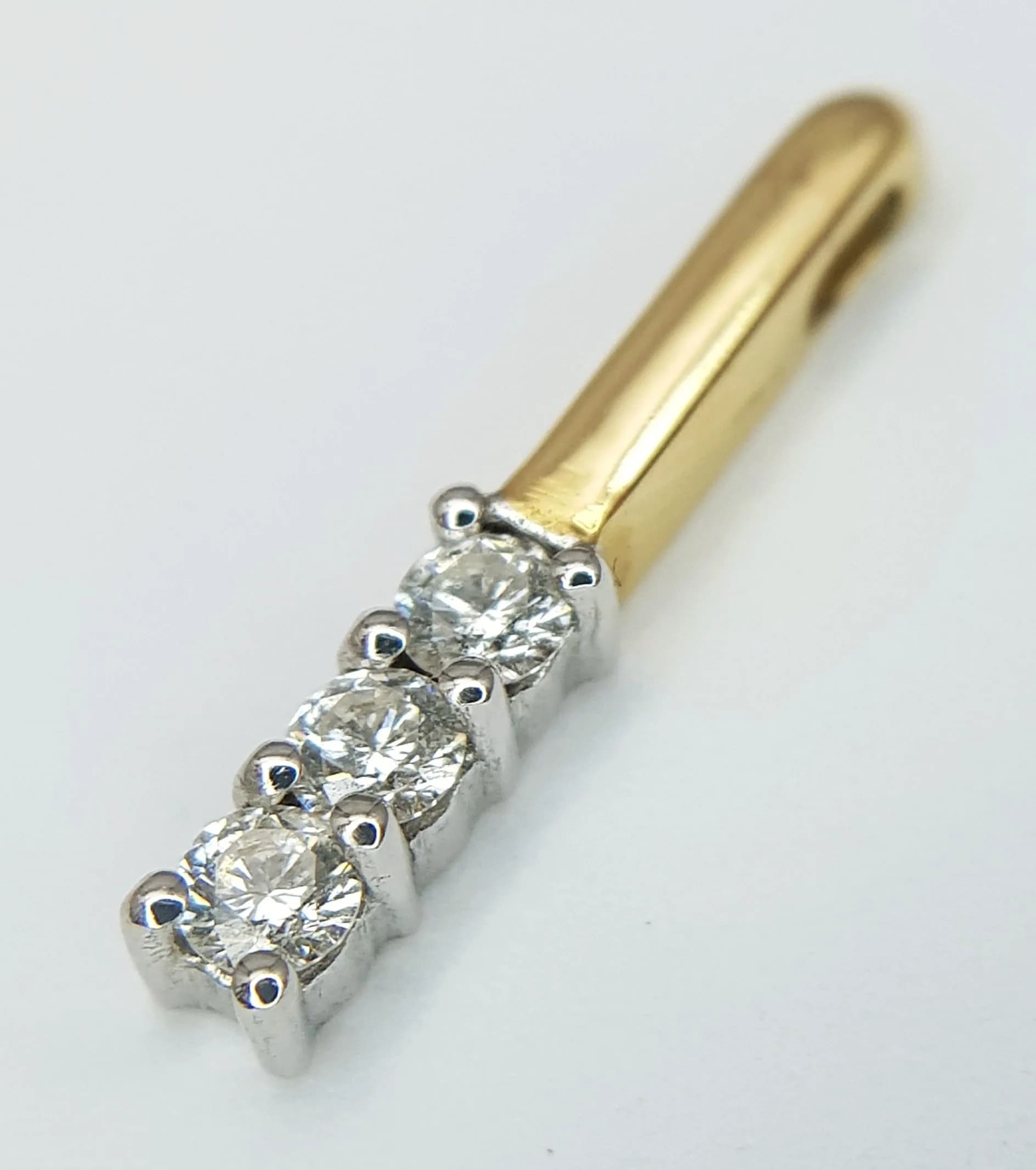 An 18K Yellow Gold and Diamond Bar Pendant. Three 0.30ctw of round brilliant cut diamonds. 2cm. 1.5g.
