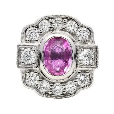 A Platinum Oval Cut Pink Sapphire and Diamond Ring. Centre Pink Sapphire Weighing 1.00ct, surrounded by Diamonds Weighing Total 0.65ct. Total Ring Weight 8.22g, Size M. Ref: 017813