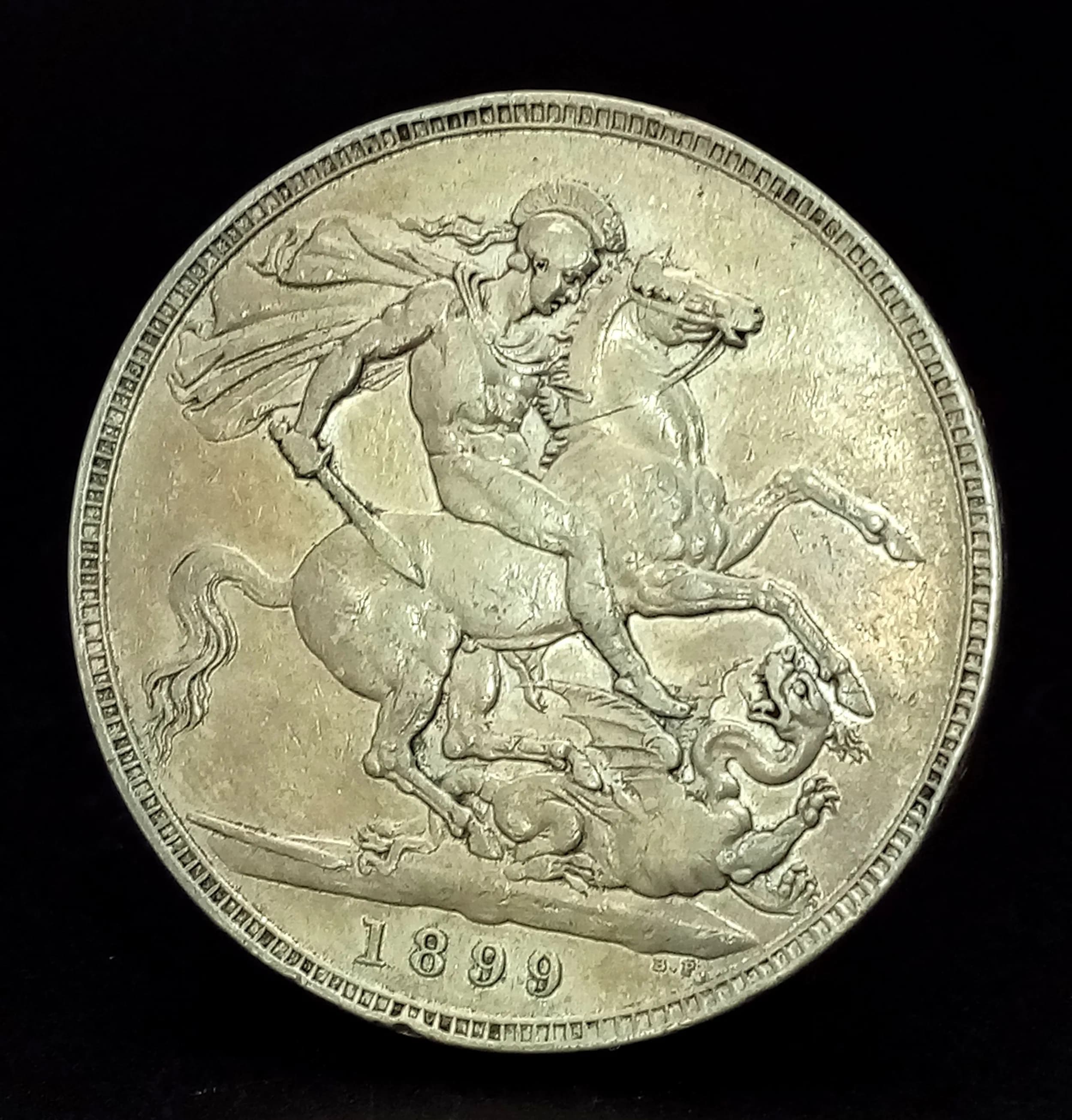 A Queen Victoria 1899 Silver Crown Coin. Obverse with old head portrait of Queen Victoria, reverse with St George and the Dragon design. Dated 1899.