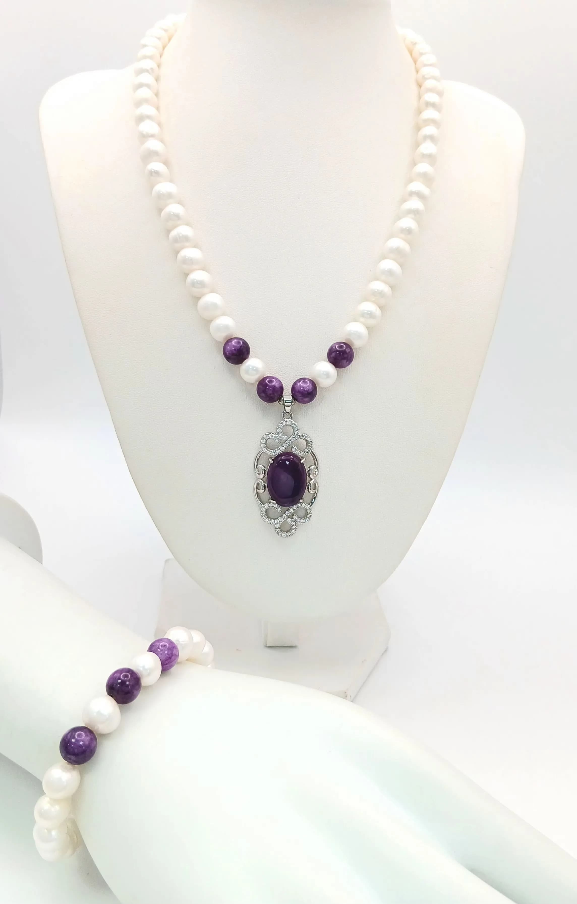 A Lovely Freshwater Pearl and Amethyst Bead Necklace and Bracelet Set. The Necklace measures 43cm in length and is strung with cream freshwater pearls and purple amethyst-style bead highlights, with an ornate purple stone pendant drop. The matching Bracelet measures 17cm in length with similar pearl and purple stone bead detail. Please see photos for details.