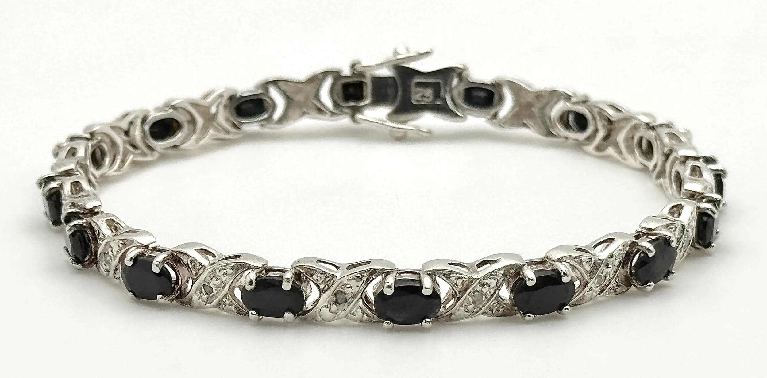 A Pleasing Sterling Silver Sapphire and Diamond Tennis Bracelet- 19.5cm Length. Set with Sixteen Blue Oval Cut 6 x 4mm Sapphires, circa 8 carat total and Sixteen Round Cut Diamonds approximately 0.15-0.16 carat. The Bracelet weighs 15.02 grams