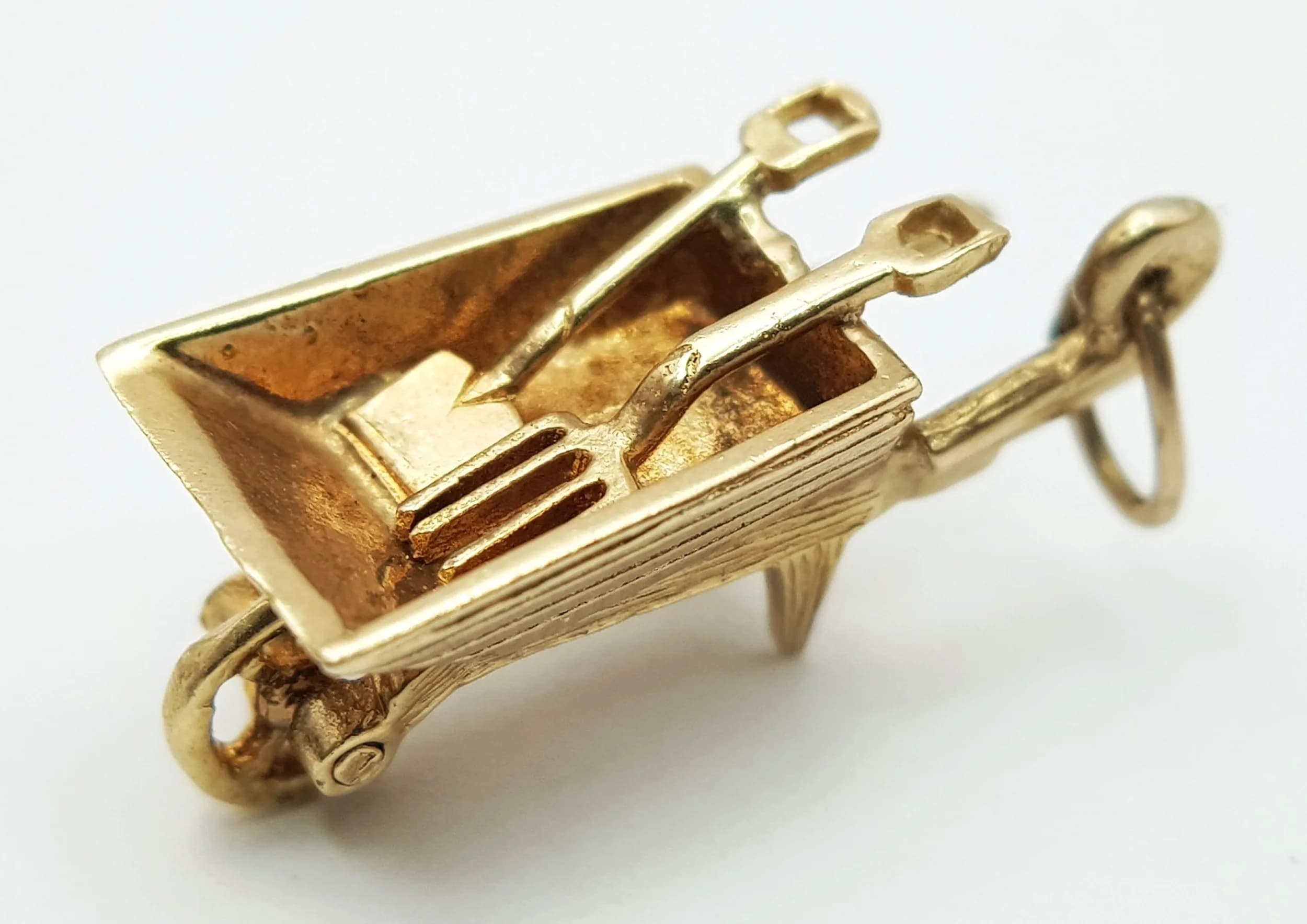A 9K YELLOW GOLD, WHEELBARROW CHARM / PENDANT. HAS A SPADE AND FORK INSIDE IT AND THE WHEEL MOVES. 2.6G. SC 5001