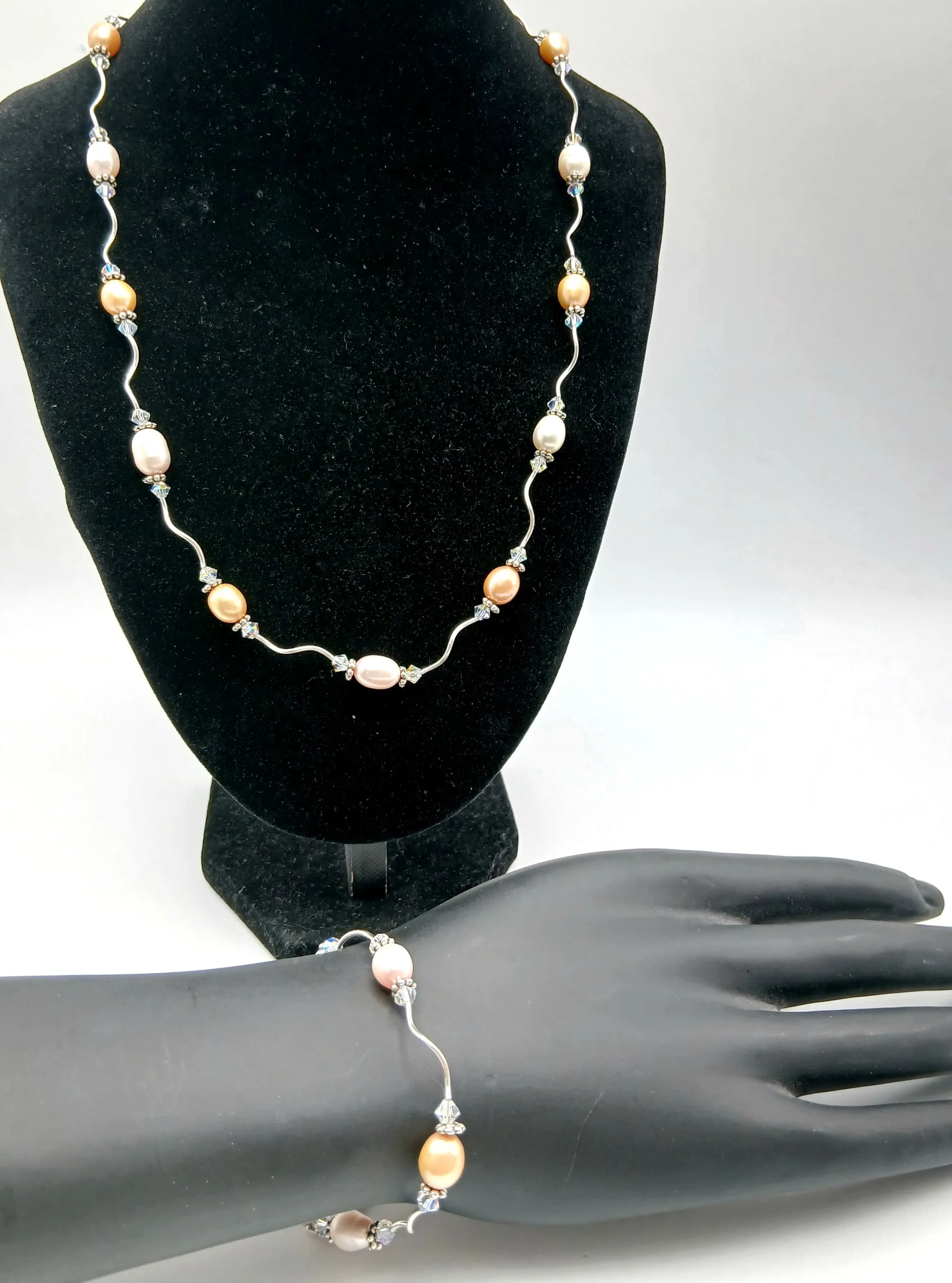 A Lovely Silver and Freshwater Pearl Necklace and Bracelet Set. Comprising a 48cm length necklace and 17cm length bracelet, each set with mixed pink, white and golden tone freshwater pearls, joined by silver wavy wire links.