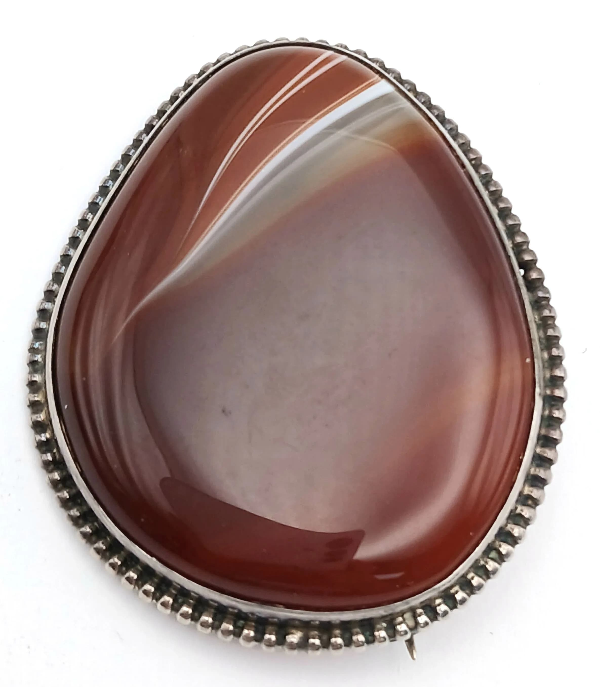 A Silver Carnelian Set Brooch. Set with a large pear shaped carnelian cabochon in a beaded silver mount. Approx 4cm x 5cm. Total weight 2.63 grams.