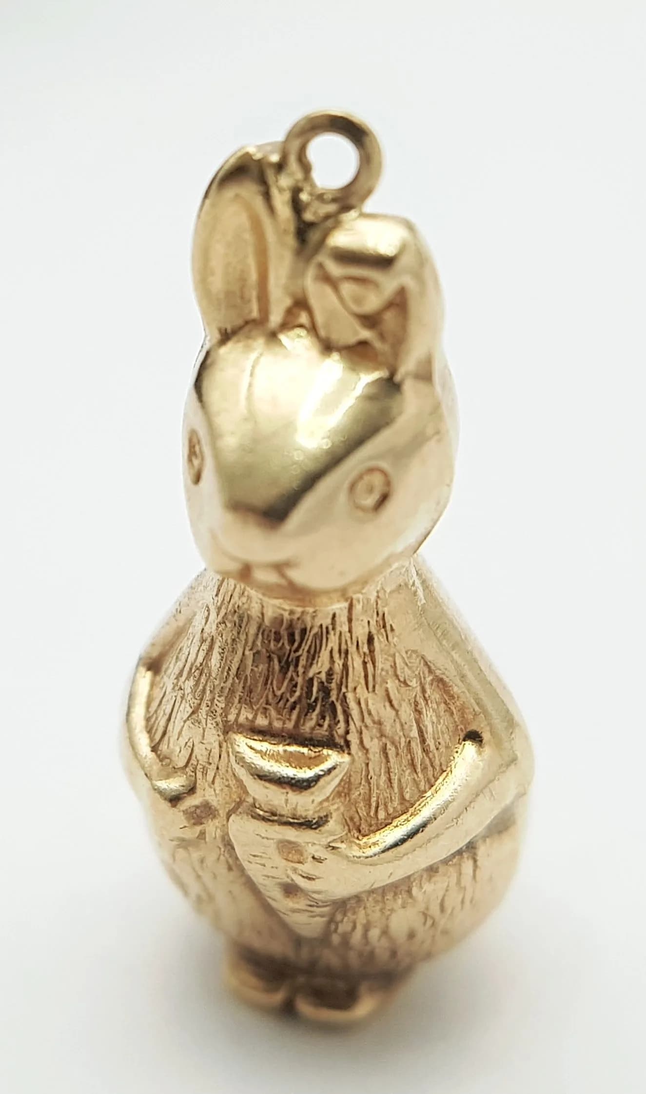 A 9K YELLOW GOLD, BUNNY RABBIT, IN THE STYLE OF PETER RABBIT, HOLD A CARROTT CHARM / PENDANT. NEEDS A JUMP RING. 1.1G. SC 5022