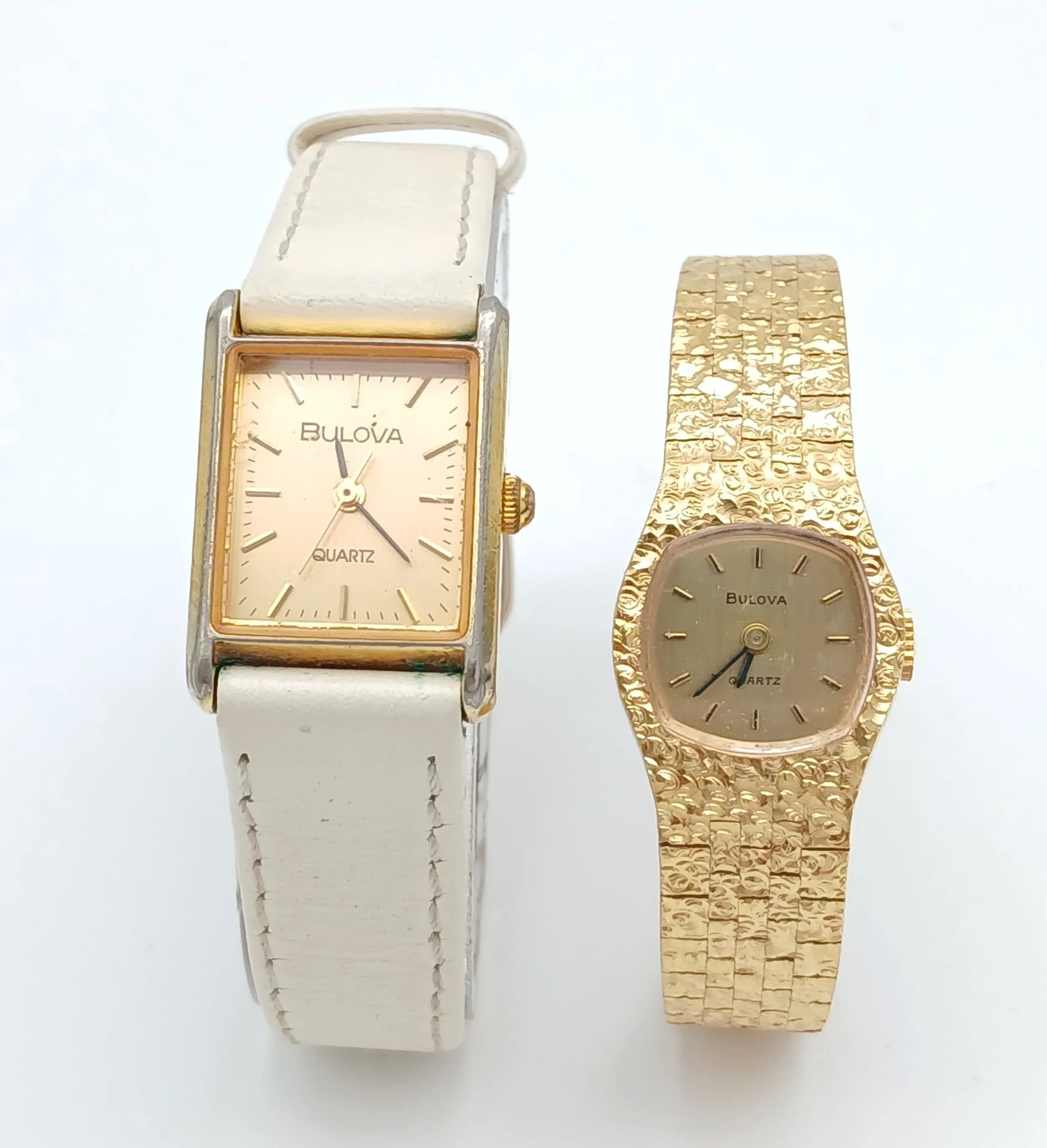 A PAIR OF BULOVA QUARTZ WATCHES. ONE GOLD TONE BRACELET AND ONE WHITE LEATHER STRAP. BOTH IN WORKING ORDER. WITH ONE ORIGINAL BULOVA WATCH BOX. S/A 1683 - 1