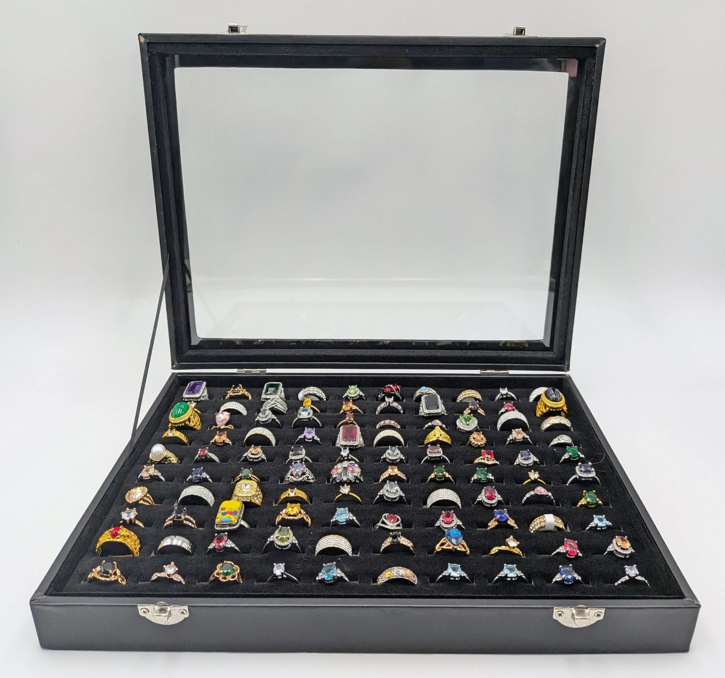 A Jewellery Display Case with 100 Rings! An absolutely fabulous lot with different colored stones to acrylic/resin decoration. All types of stone cuts with gilded and white metal shanks of different design. Sizes range from small to large. All rings in excellent condition. Case size - 35 x 24cm.