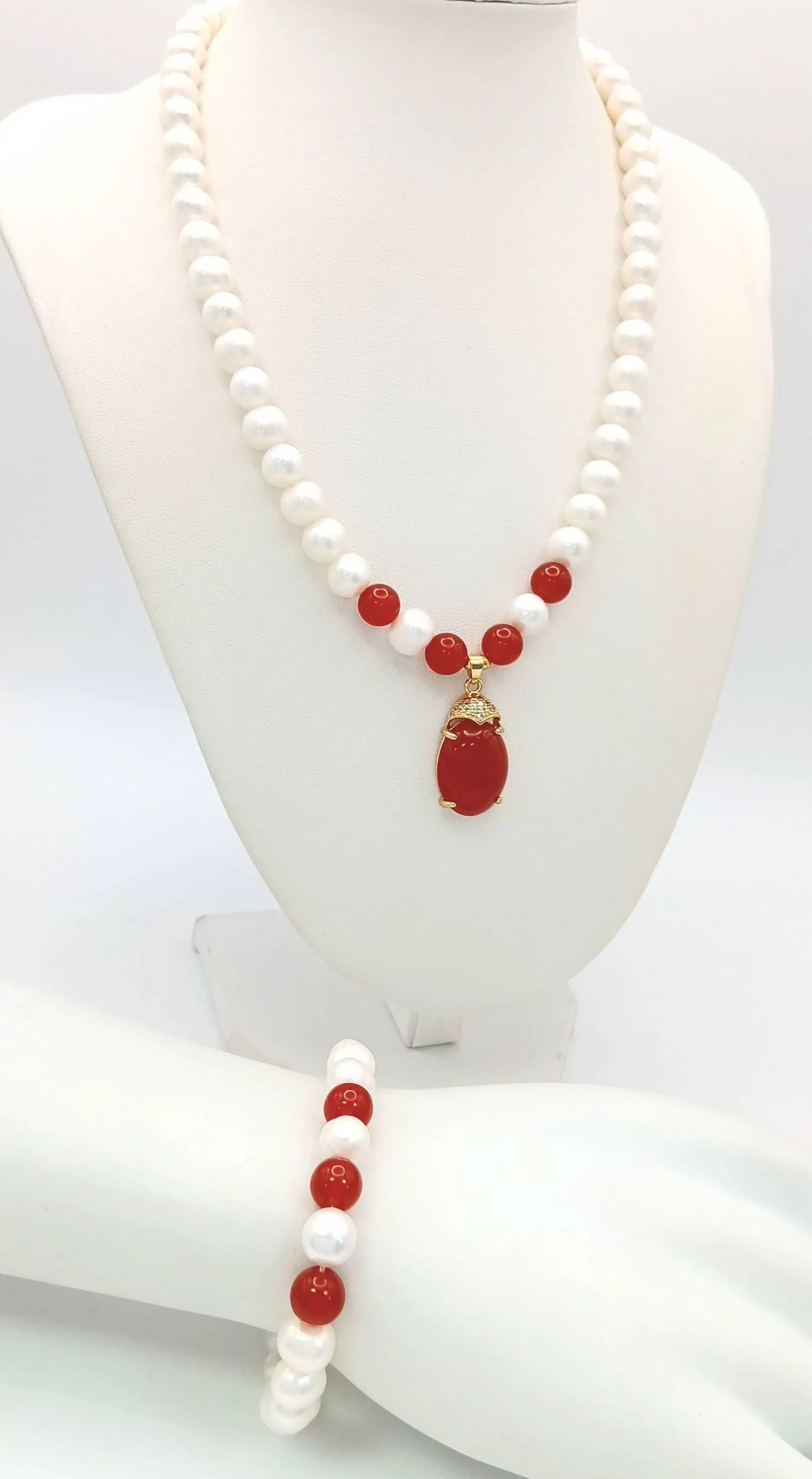 A Lovely Freshwater Pearl and Red agate stone set Necklace and Bracelet Set. The Necklace measures 44cm in length and is strung with cream freshwater pearls and red agate bead highlights, with a large oval agate pendant drop. The matching Bracelet measures 18cm in length with similar pearl and red agate bead detail. Please see photos for details.