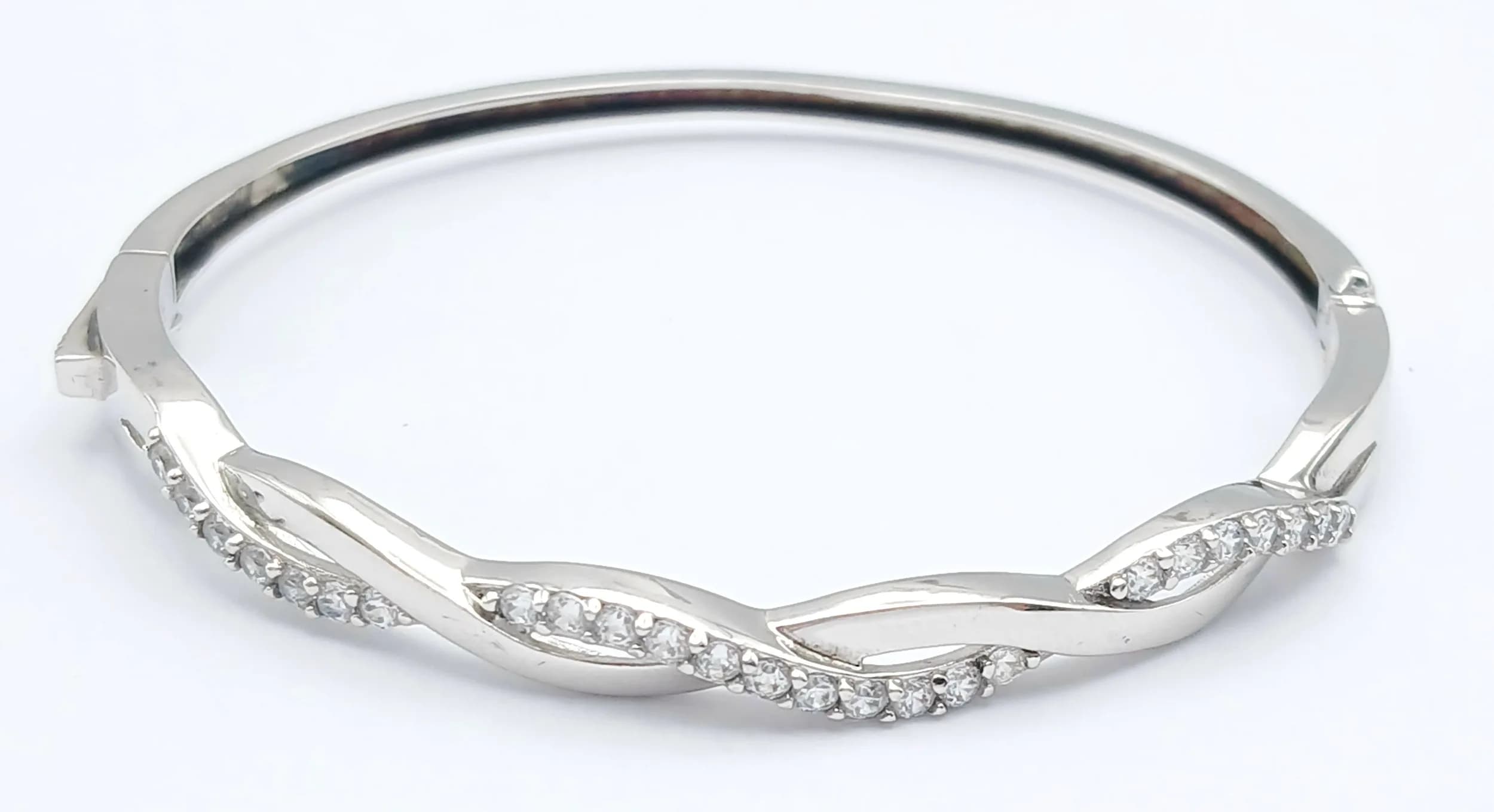 A Stunning 925 Silver CZ Stone Set Bangle. Featuring a polished silver twist design with CZ stone set woven detail. Approx 6cm diameter. Gross weight 8.92 grams.