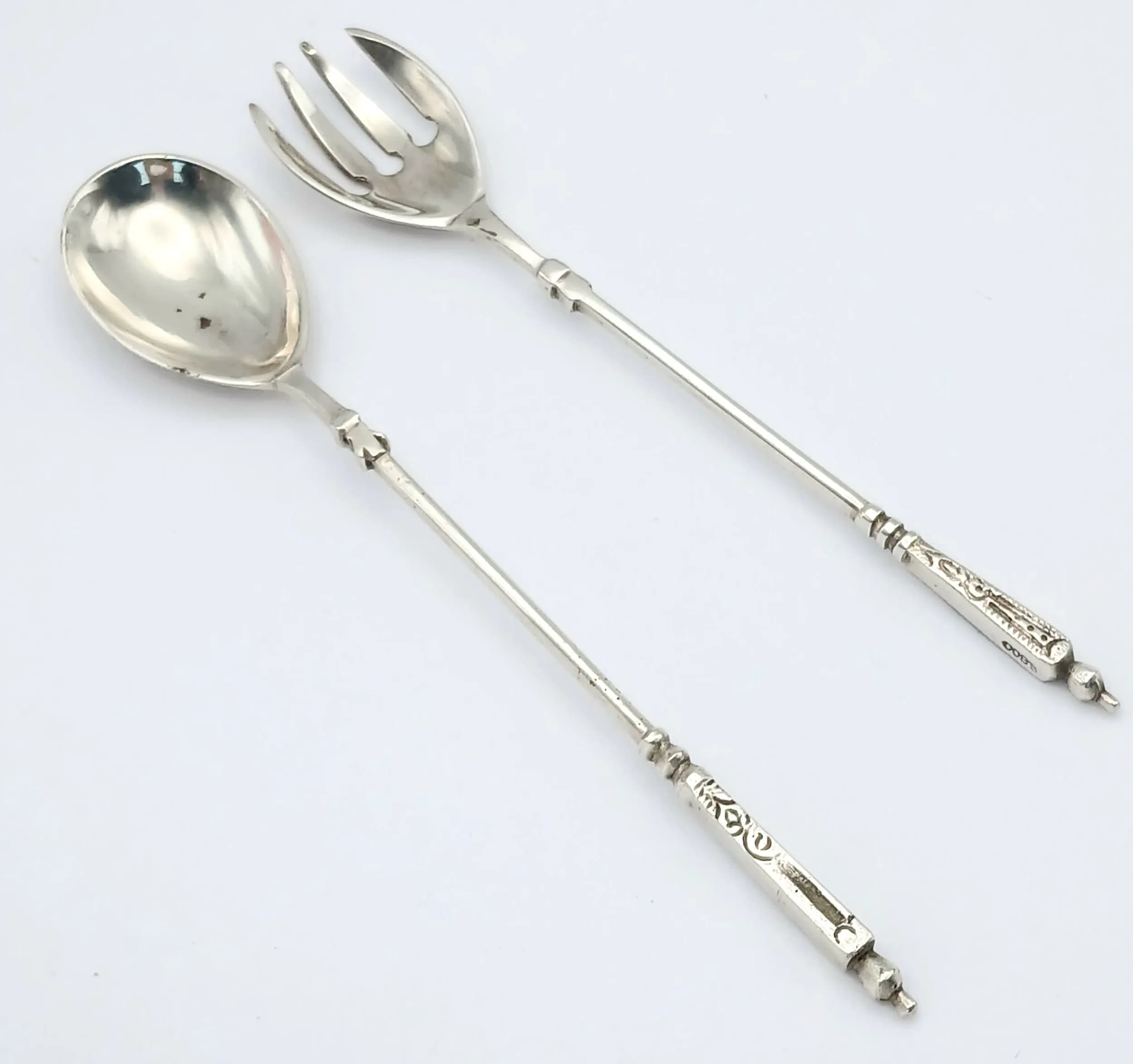 A Pair of Vintage 800 Silver Dessert Servers. Comprising a small dessert spoon and fork, each with decorative engraved handle detail. Approx 14cm length. Total weight 30.55 grams.