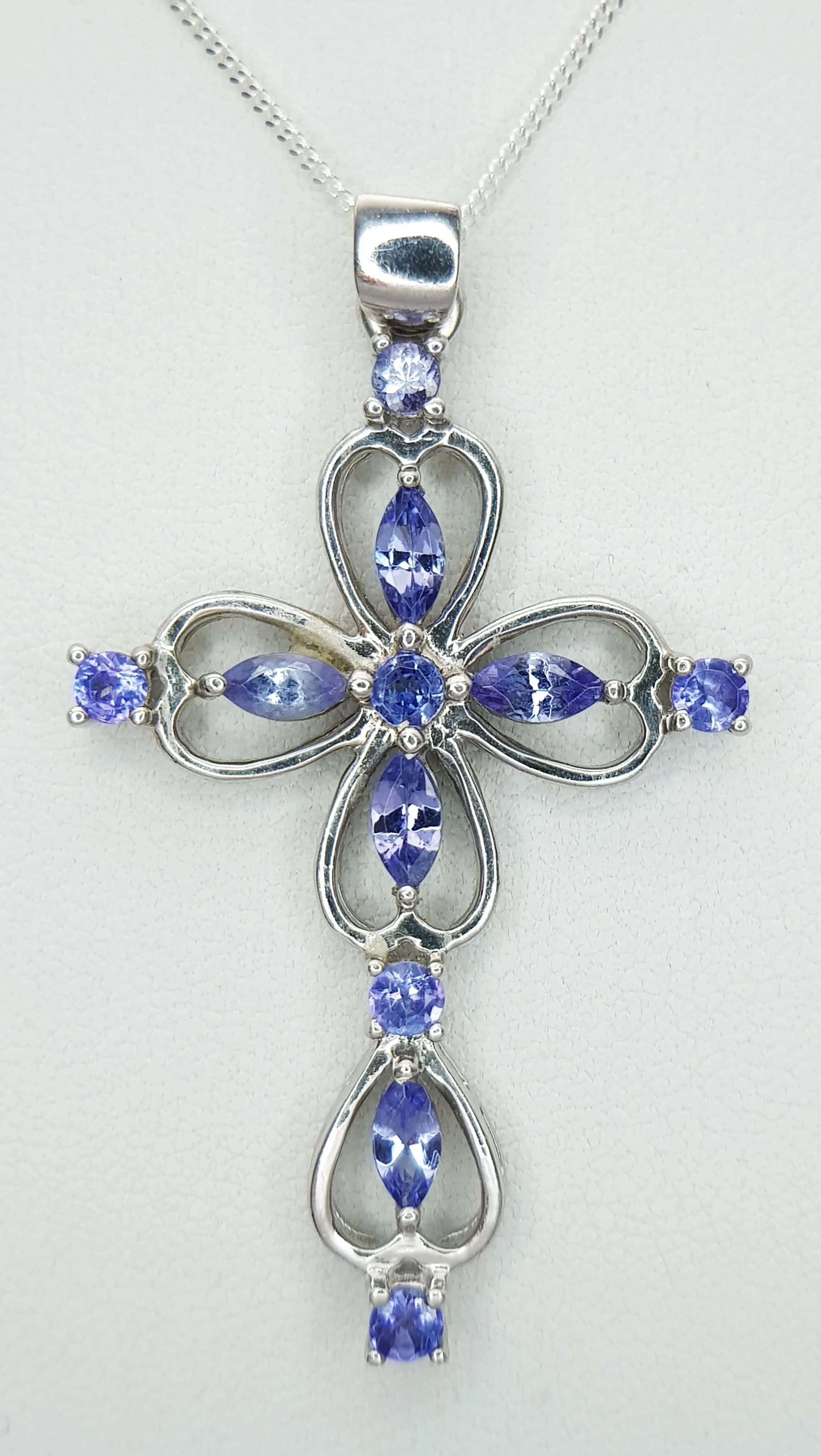 A Beautiful Sterling Silver Tanzanite Set Cross Pendant Necklace-46cm Length. The Cross measures a 5.3cm drop and is 2.9cm wide being set with round and marquise cut Tanzanite. The Necklace has a gross weight of 7.43grams.