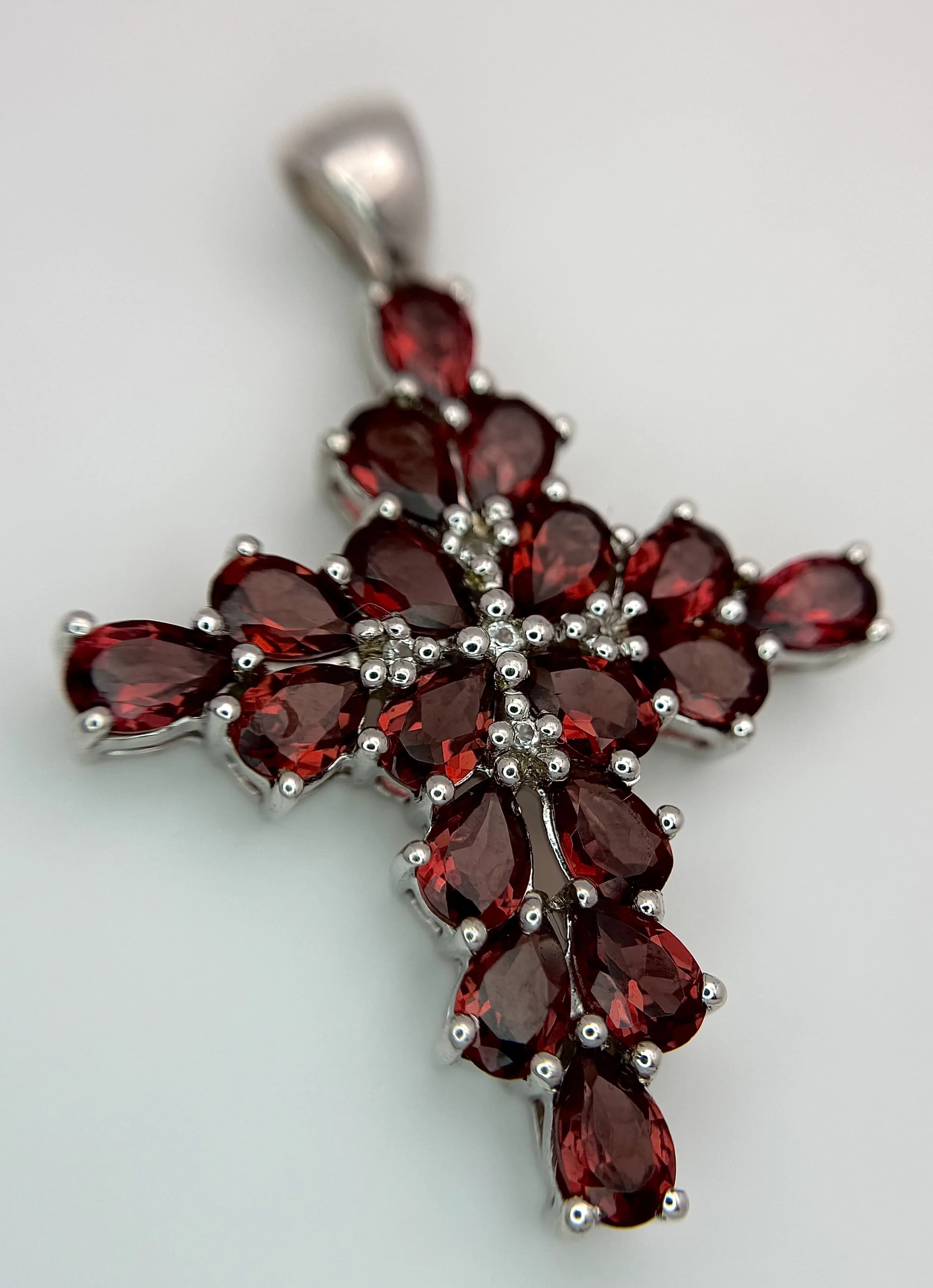 A Stylish Sterling Silver Red Garnet Cross Pendant. 4.5cm drop, 3.2cm width. Set with Eighteen 5 x 4mm Pear Cut Garnets, approximately 6.5 carat Total. Gross weight 8.55 grams.