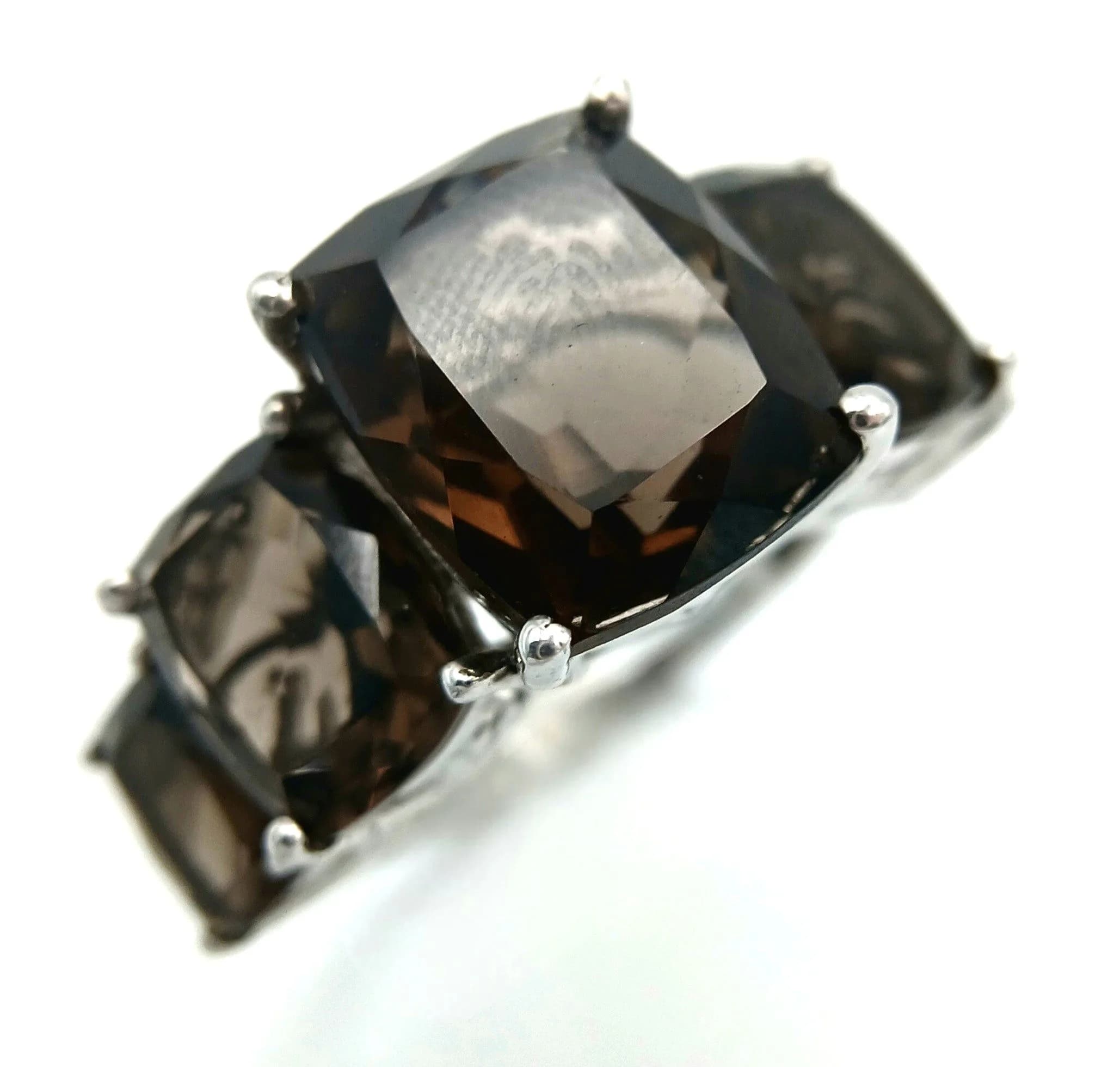 An Impressive Sterling Silver Graduating Size Five Stone Smoky Quartz Ring-Size P. The Ring is set with five fancy rectangle step cut Smoky Quartz ranging from 6 to 12mm Lengths. The Ring has a gross weight of 5.4 grams.