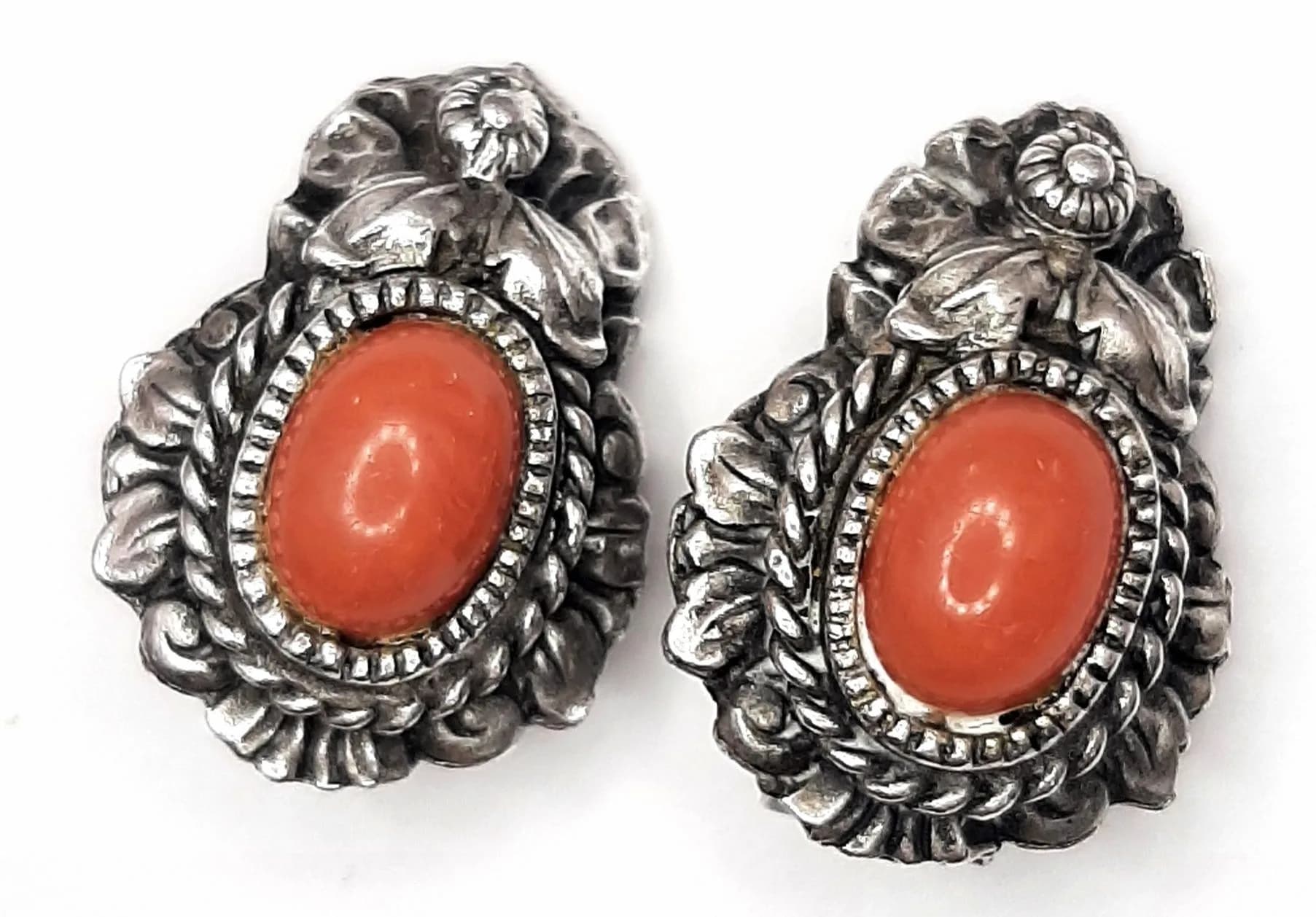 A Vintage Beautiful Pair of 925 Silver Red Coral Clip On Earrings. Each earring set with an oval red coral cabochon in a decorative silver floral mount. Approx 1.5cm x 2.5cm. Total weight 10.85 grams.