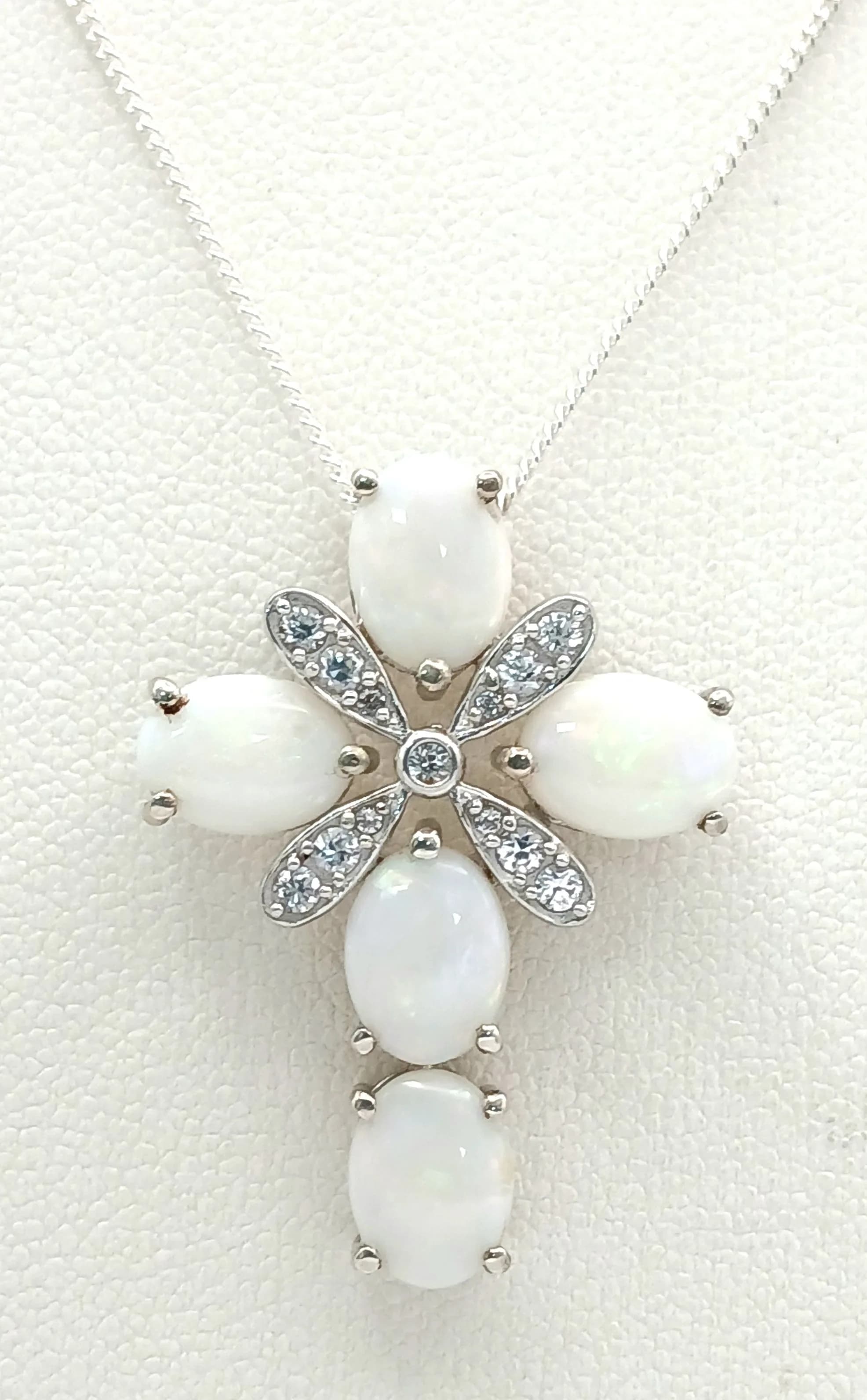 A Beautiful Sterling Silver Opal and White Topaz Cross Pendant Necklace- 46cm Length chain. The Cross measures 3 x 2.2cm and is set with five 8 x 6mm Oval Cut Opals, approximately 5 carat total and with Round Cut WhiteTopaz. The Necklace has a gross weight of 5.73 grams.