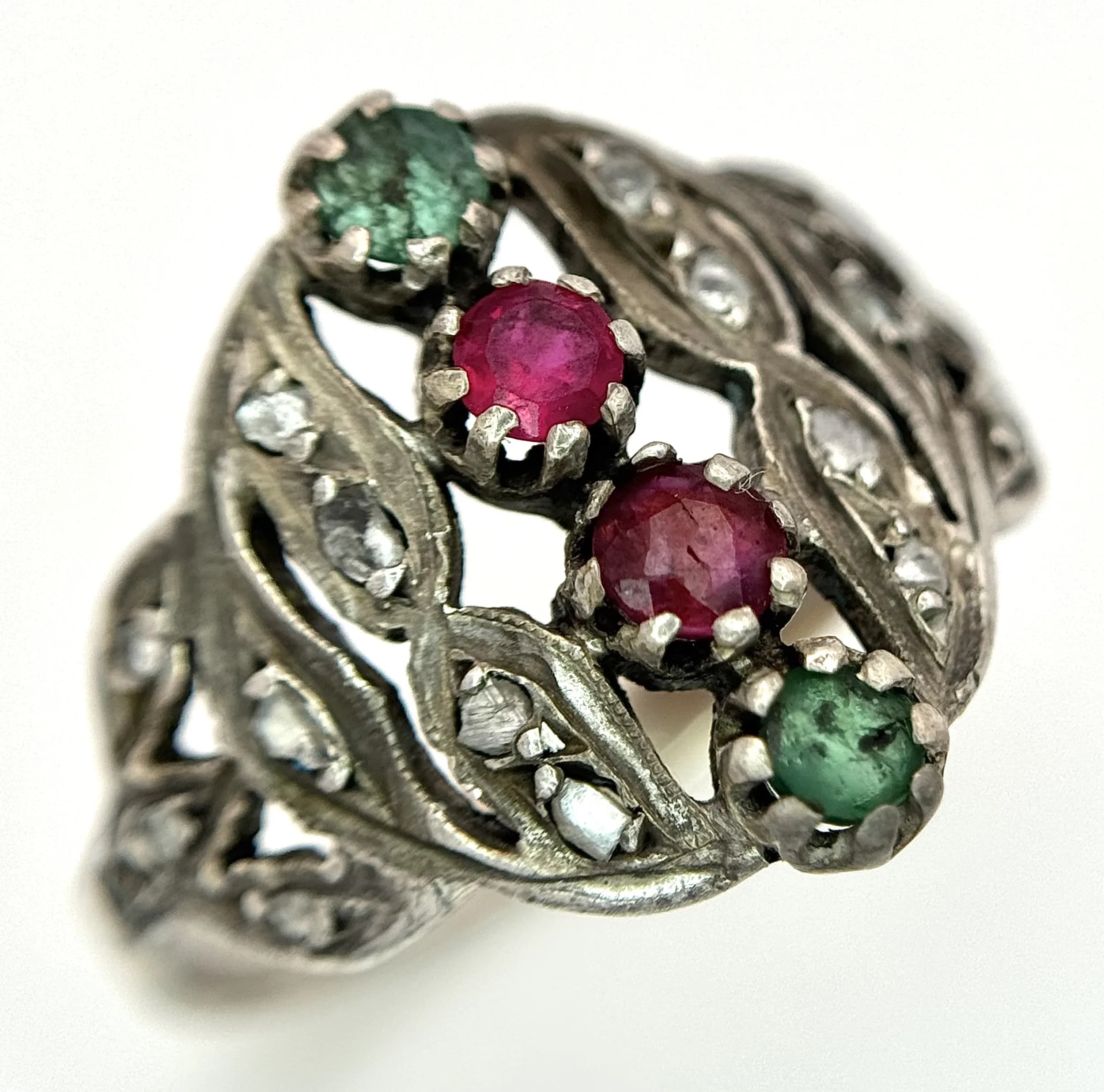 An Antique Gold, Silver, Ruby and Emerald Ring. The band tests as 14k gold with an openwork silver setting, whereupon two very old emerald and ruby stones hold court.Old cut diamond accents complete the picture. Size R 1/2.3.6g total weight.