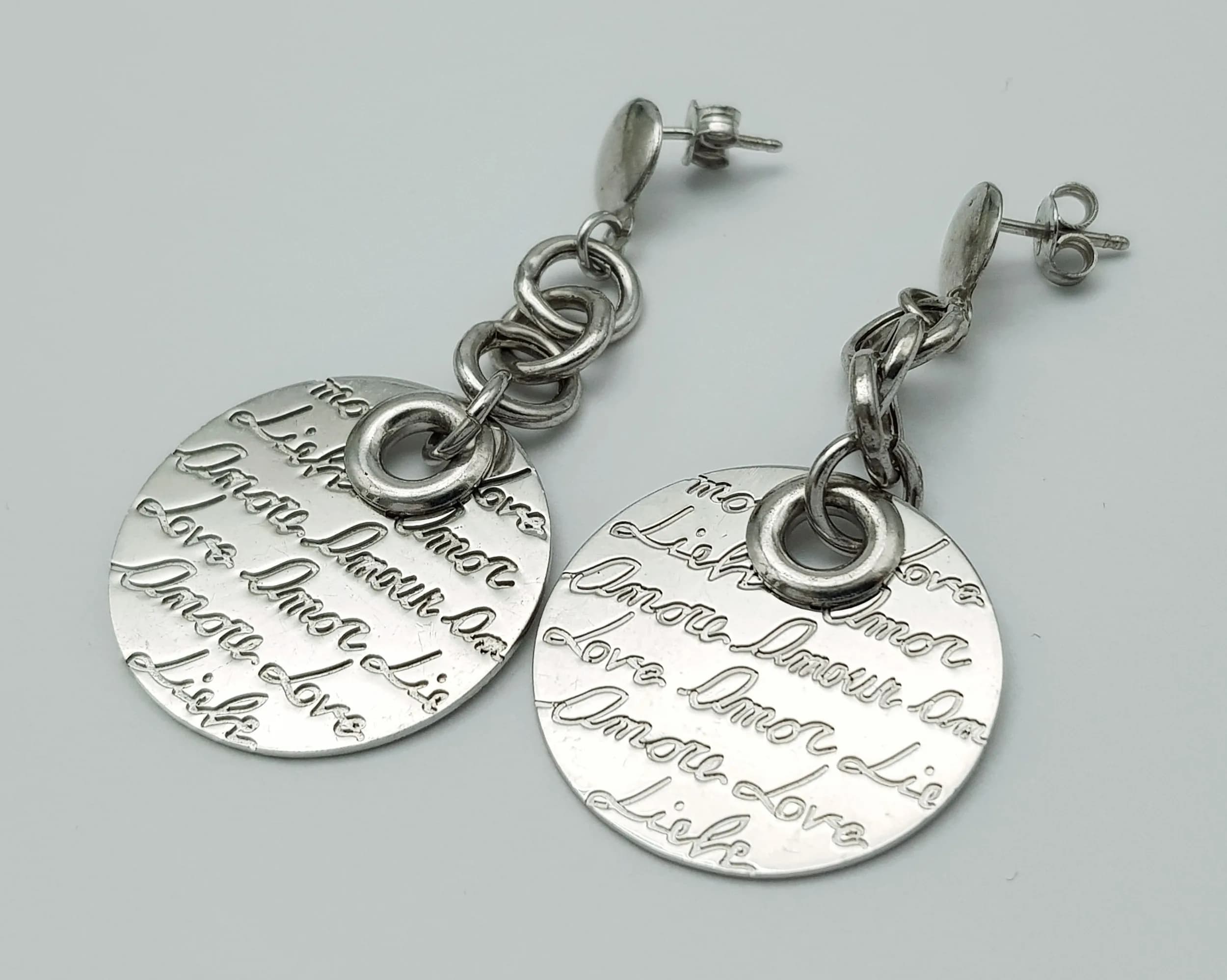 A Pair Of Sterling Silver, Drop Earrings. Engraved With The Word Love In Many Languages. 10.7G. J Sil 4002