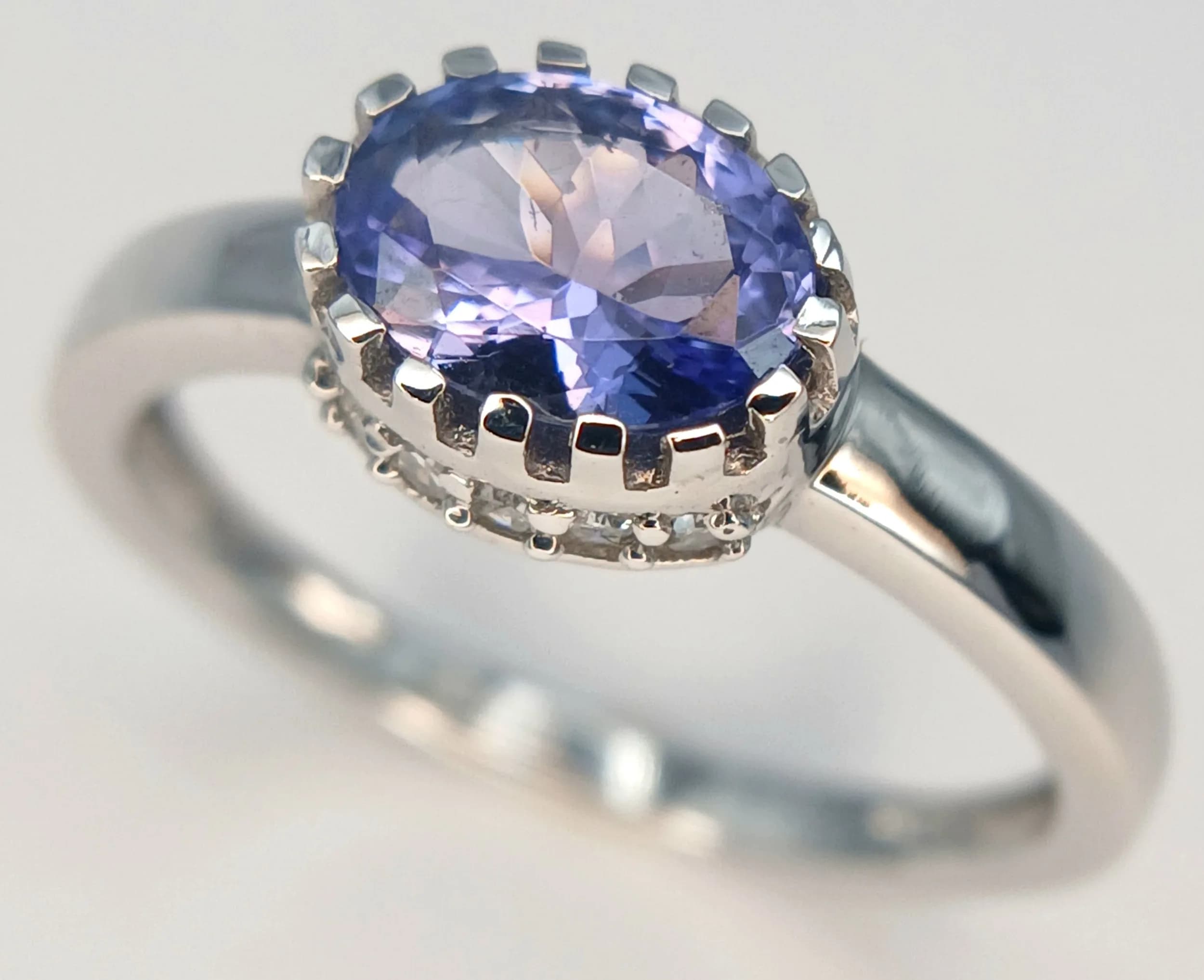 A 9k White Gold Tanzanite and Diamond Set Ring Size O. The Ring is set with a 7 x 5mm Oval Cut Tanzanite (circa 0.75 carat) and with Ten 1mm Brilliant Round Cut Diamonds set into the sides of the mount. The Ring has a gross weight of 2.23 grams. Appears practically unworn if worn at all