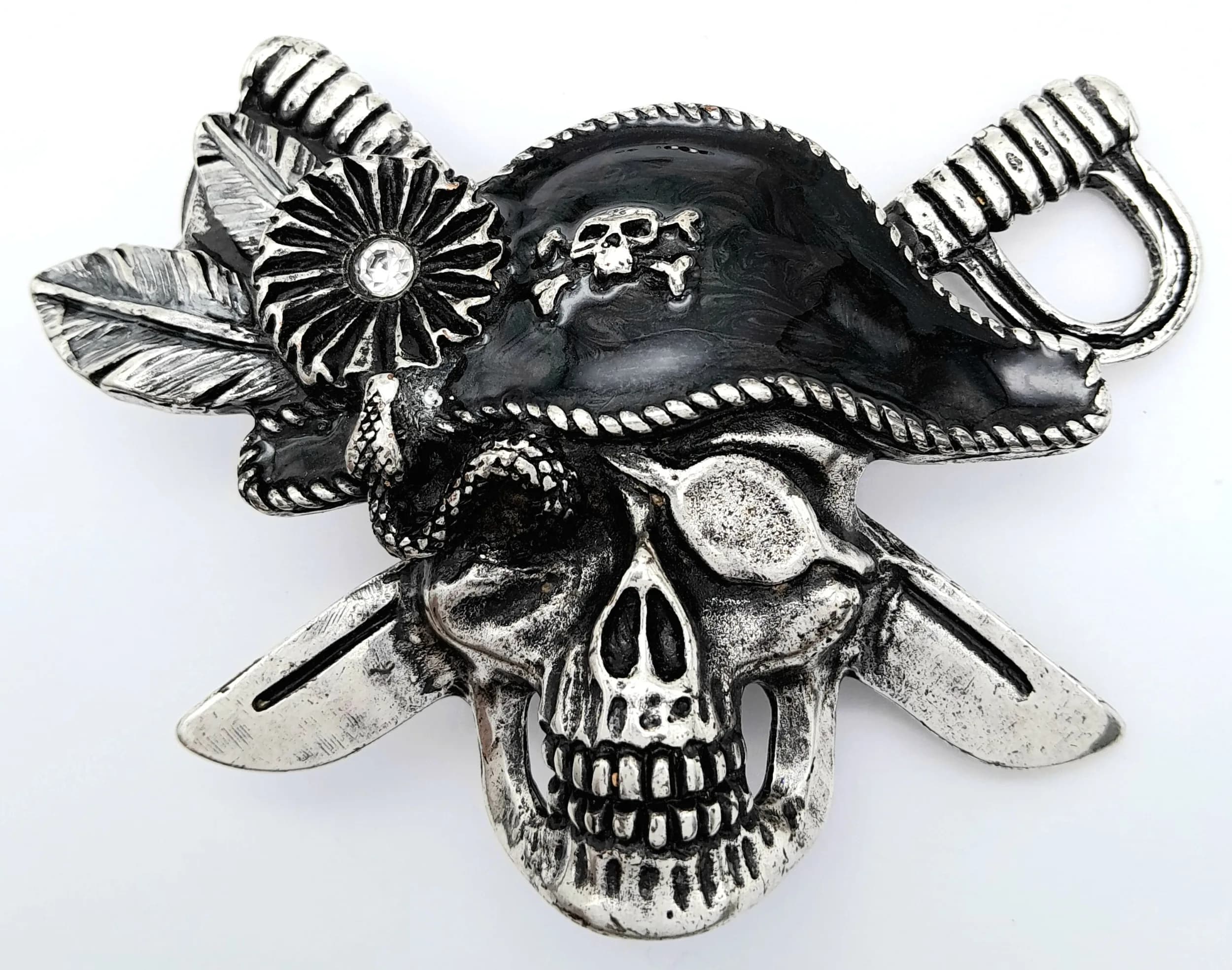 An Unusual Skull Design Scarf / Napkin Holder. Features a silver-tone skull design with black enamel-style detailing, leaf and flower decoration, with a rear bar fitting for holding a scarf or napkin. The holder measures 11cm x 8cm.