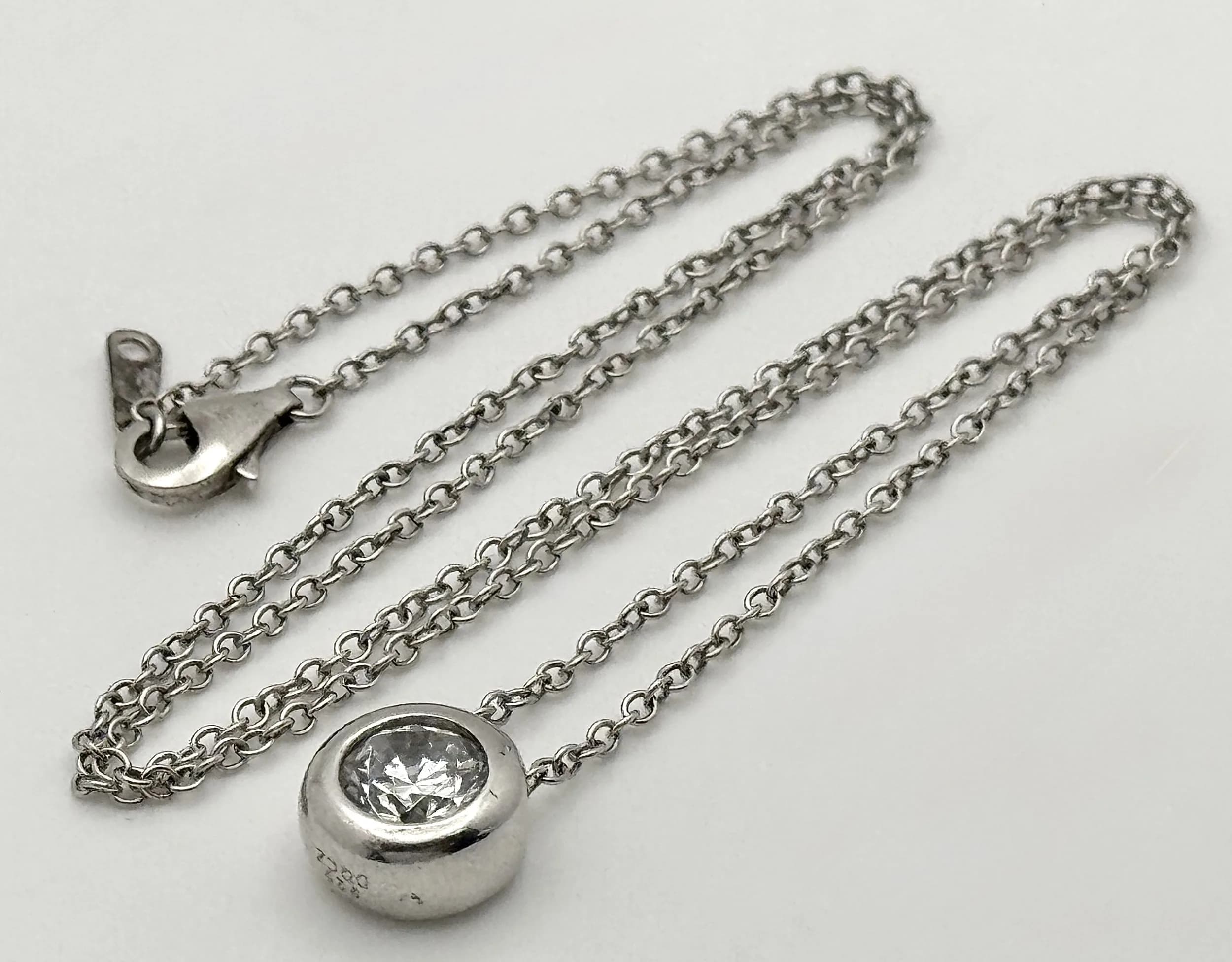 A Silver Chain necklace with a CZ stone set Circular Pendant. 42cm.