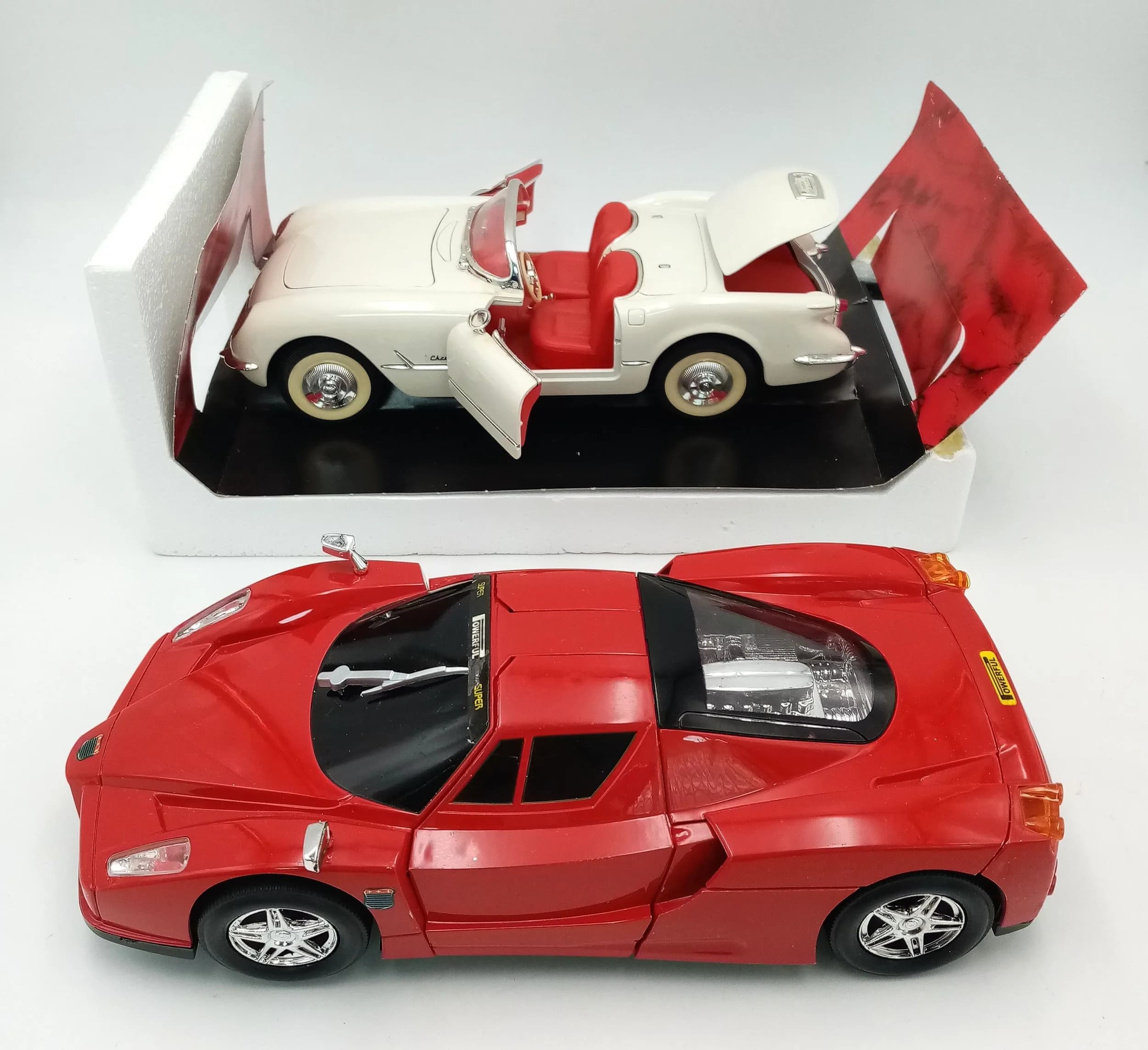 Two 1/18th scale die cast model cars. A Corvette and a Ferrari. Both in original boxes. Models in excellent condition, although the boxes show signs of wear from storage.