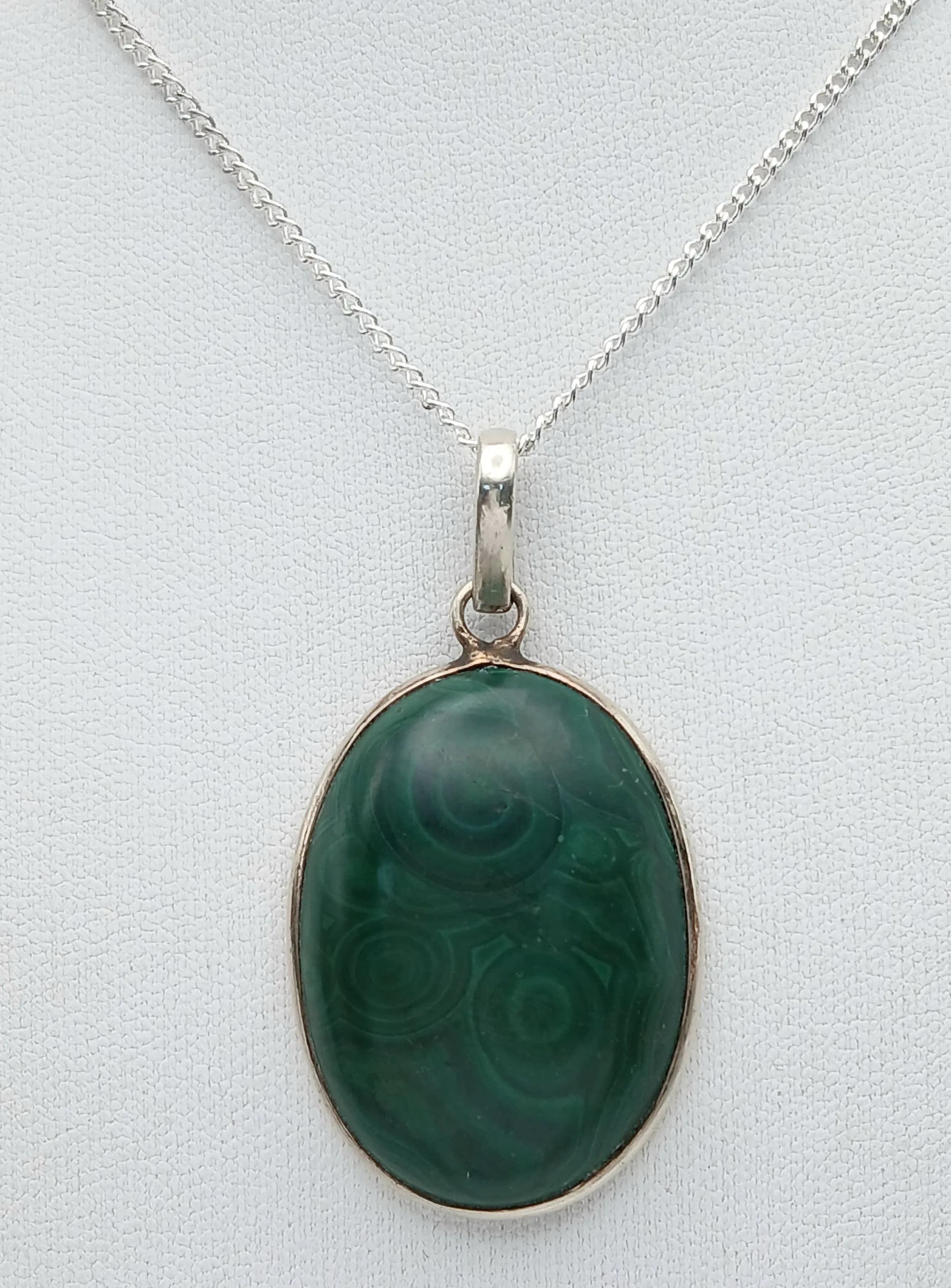 An Attractive and Unique Sterling Silver and Malachite Pendant Necklace. 46cm Length Chain. The Pendant is set with a 3.2 x 2.4cm Oval Cut Malachite Cabochon that has natural circular banding making this an eye-catching piece. The Necklace has a gross weight of 18.77 grams
