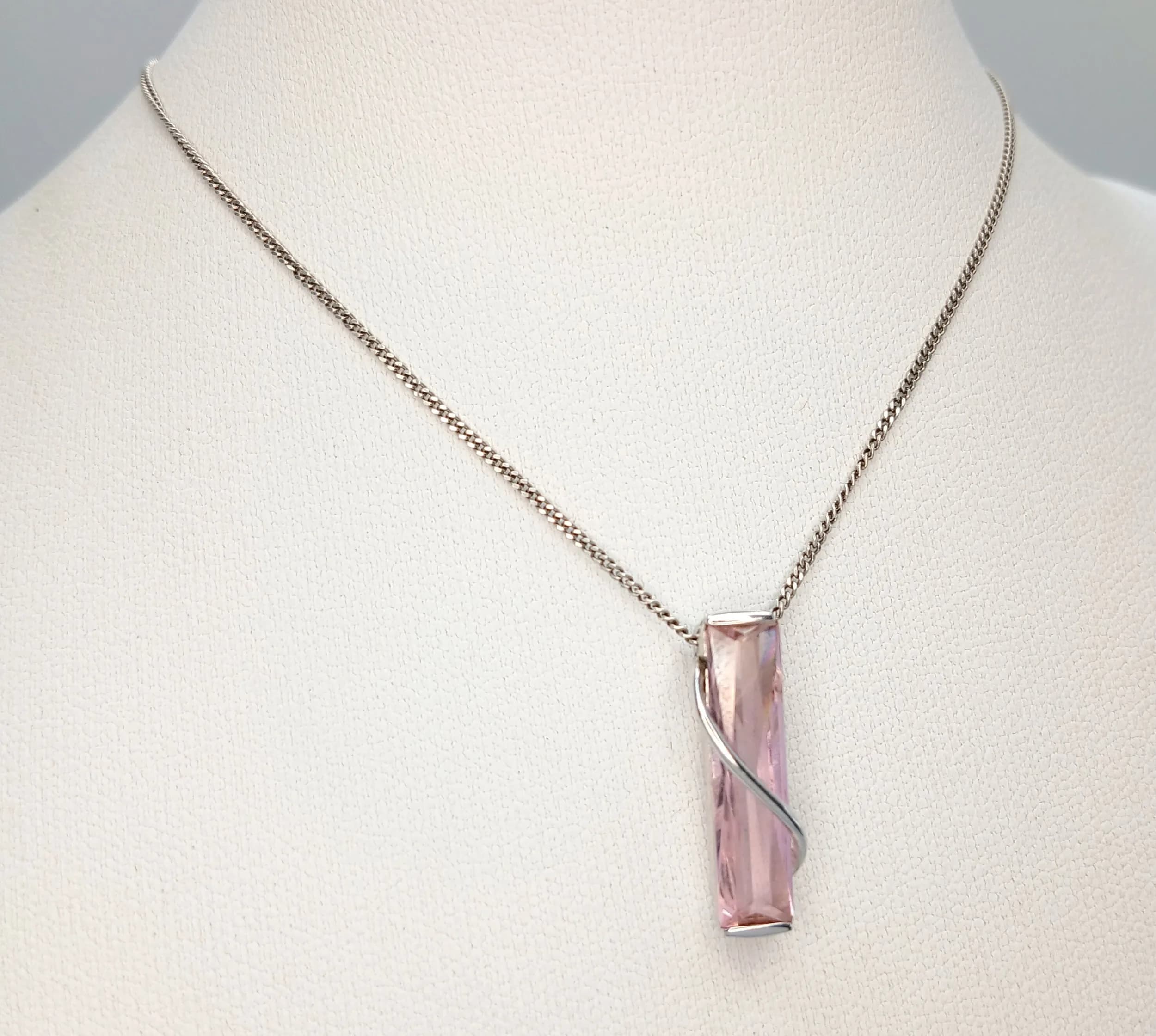 A Stunning 925 Sterling Silver Pink Crystal Pendant Necklace - 44cm Length. Features a rectangular faceted pink crystal pendant with a spiral silver overlay on a fine silver chain. The pendant measures 0.5cm x 2cm. Gross weight 3.67 grams.