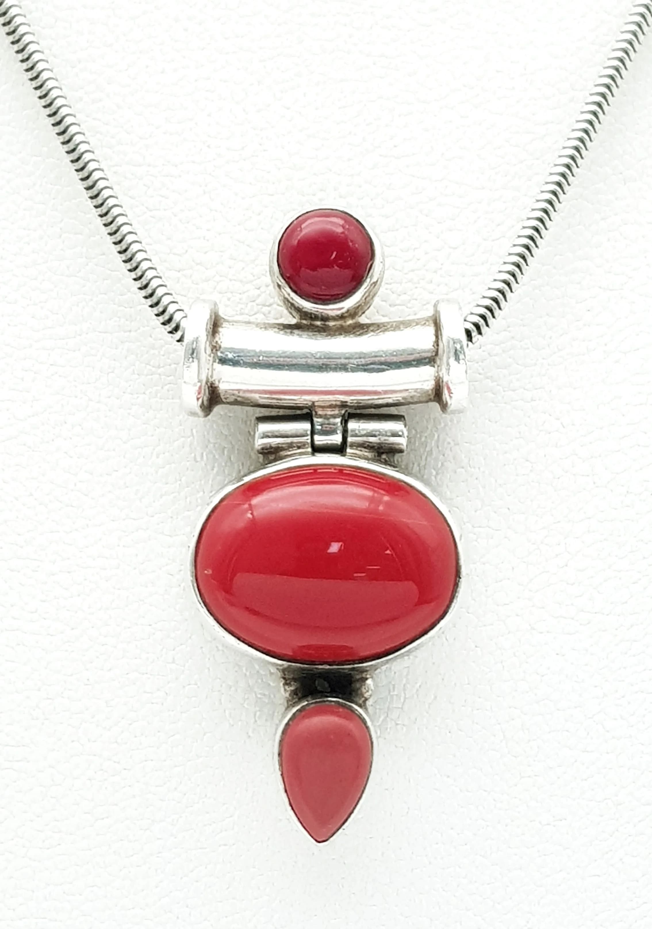 A Pretty 925 Silver Red Coral Set Pendant Necklace. Set with three red coral cabochons in a silver pendant mount. Chain approx 40cm length. Pendant drop approx 3.5cm. Total weight 10.90 grams.