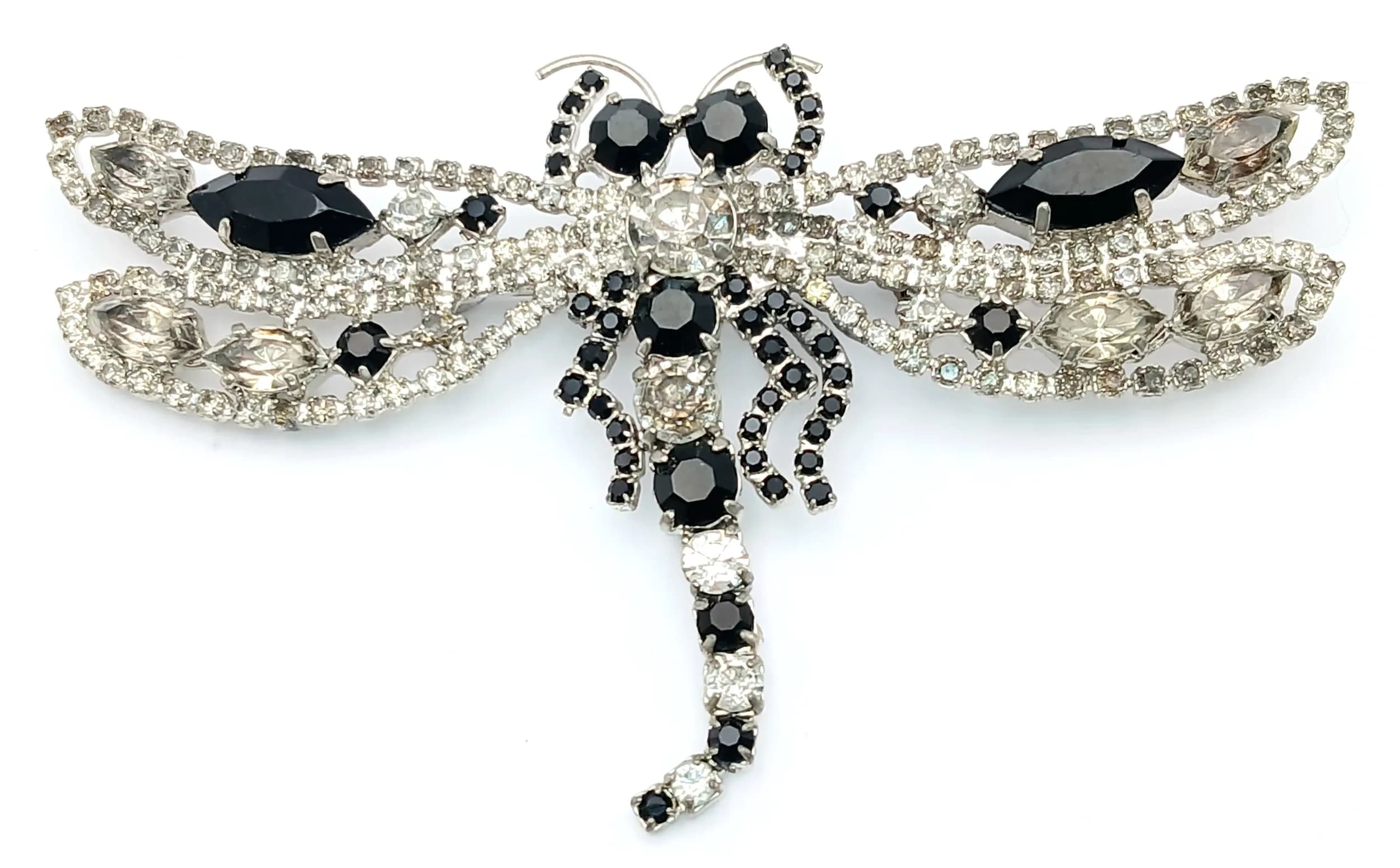 A Pretty Stone Set Dragonfly Brooch. Silver-tone dragonfly design brooch set with white and black rhinestones, with openwork wings and black marquise-cut style stones. Measures approx. 10cm x 6cm.