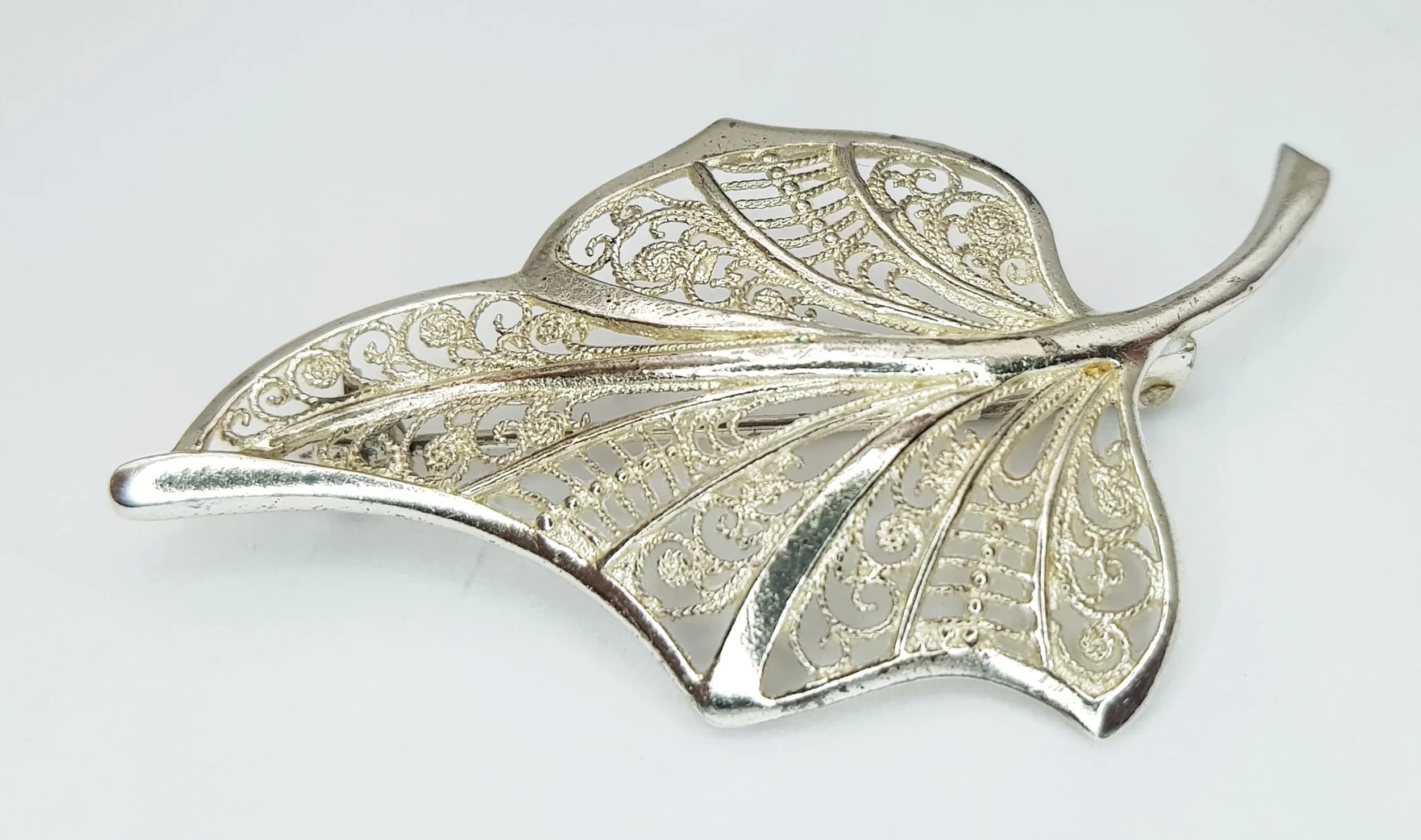 A Pretty 925 Silver Filigree Leaf Brooch. Features an intricate openwork leaf design with decorative scroll detailing. The brooch measures 5cm x 2.5cm. Gross weight 4.21 grams.