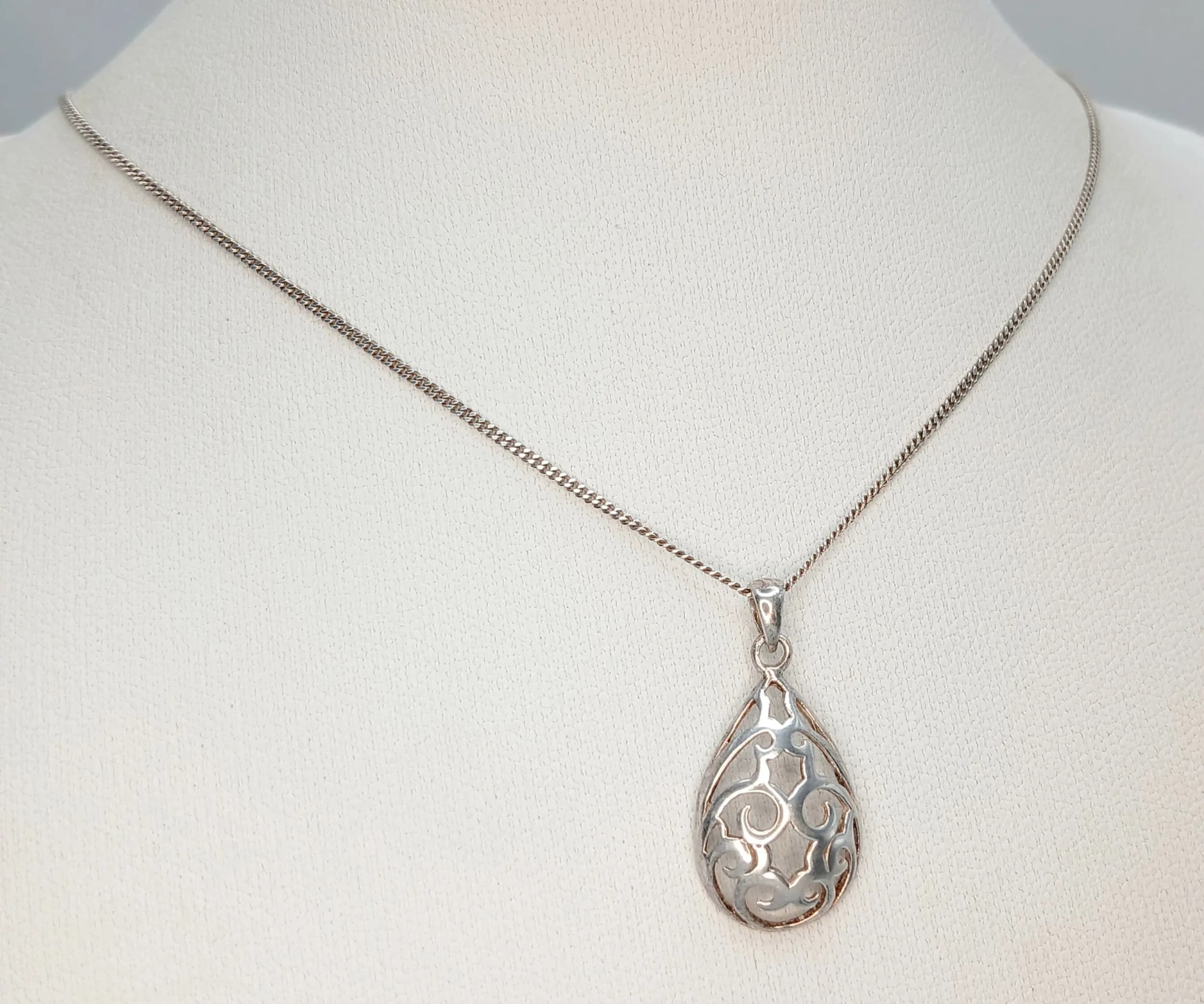 A Pretty 925 Sterling Silver Openwork Teardrop Pendant Necklace - 44cm Length. Features an ornate scrollwork teardrop pendant on a fine silver chain. The pendant measures 1.5cm x 1.3cm. Gross weight 2.45 grams.