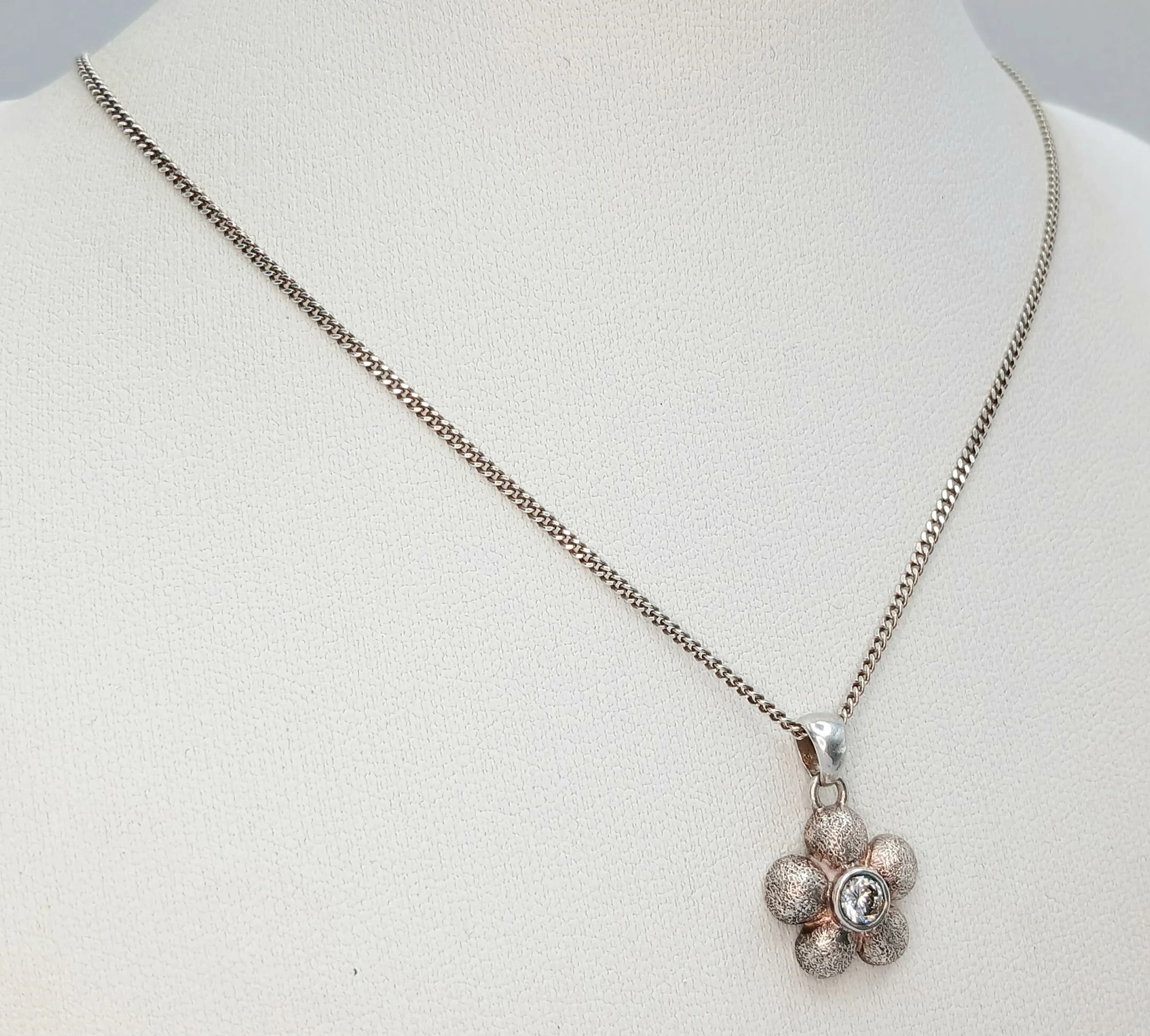 A Delightful 925 Sterling Silver CZ Set Flower Pendant Necklace. The pendant is flower-shaped and set with a central CZ stone. The necklace measures 40cm length. The pendant measures 1.5cm drop. The necklace has a gross weight of 4.07 grams.