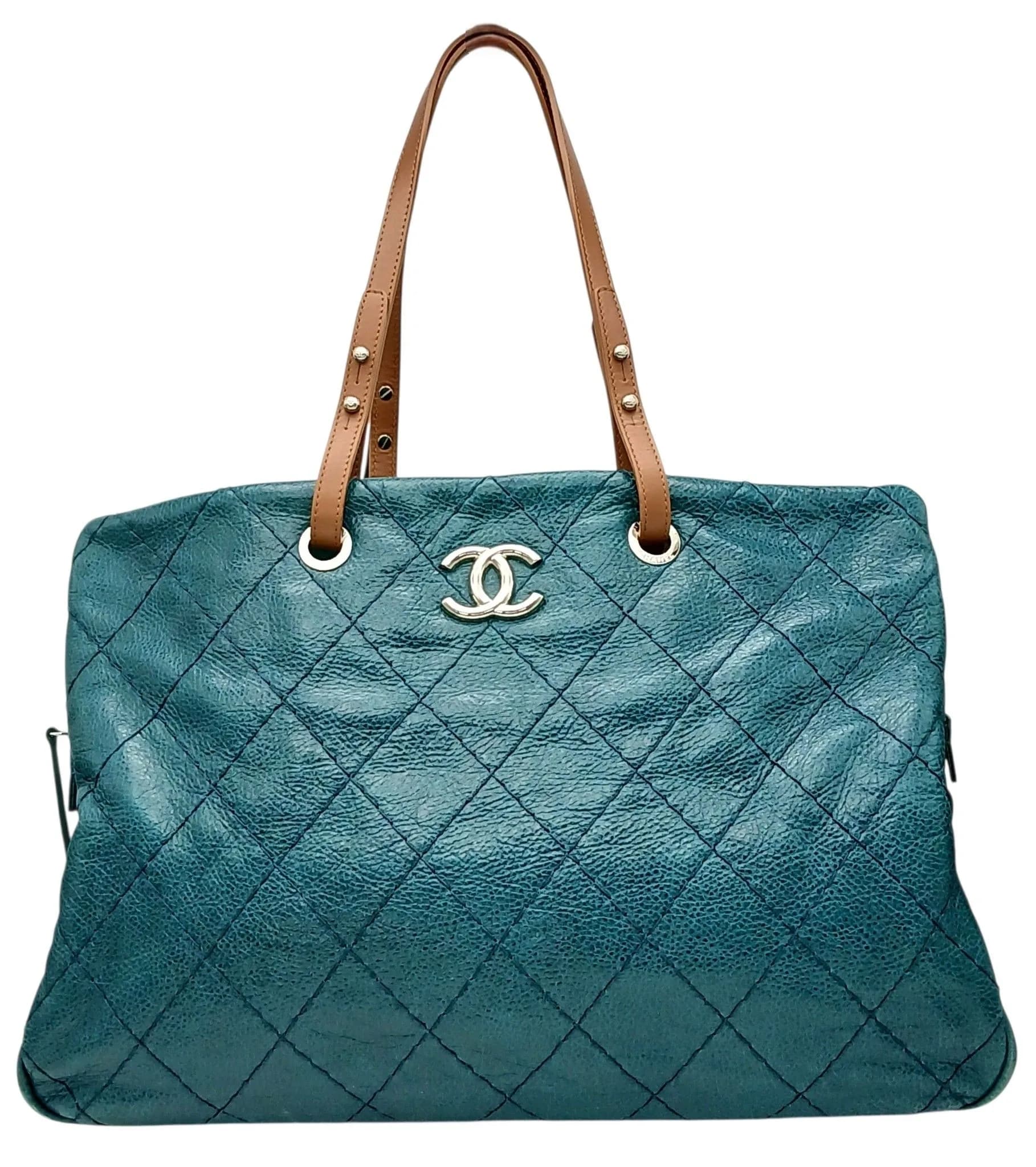 A Chanel Quilted Leather Tote Bag. Dark teal quilted leather exterior with silver-toned hardware, CC logo detail, tan leather shoulder straps and protective base studs. Open-top design opens to a charcoal-blue textile interior with two main compartments, a central zipped compartment, two open inner side pockets, and a zipped inner side pocket. Comes with a certificate of authenticity and an authenticity card. Approx 44cm length x 31cm height. Some light signs of wear to the base corners, but in good overall condition. Please see photos or request a condition report. Ref: 29063.