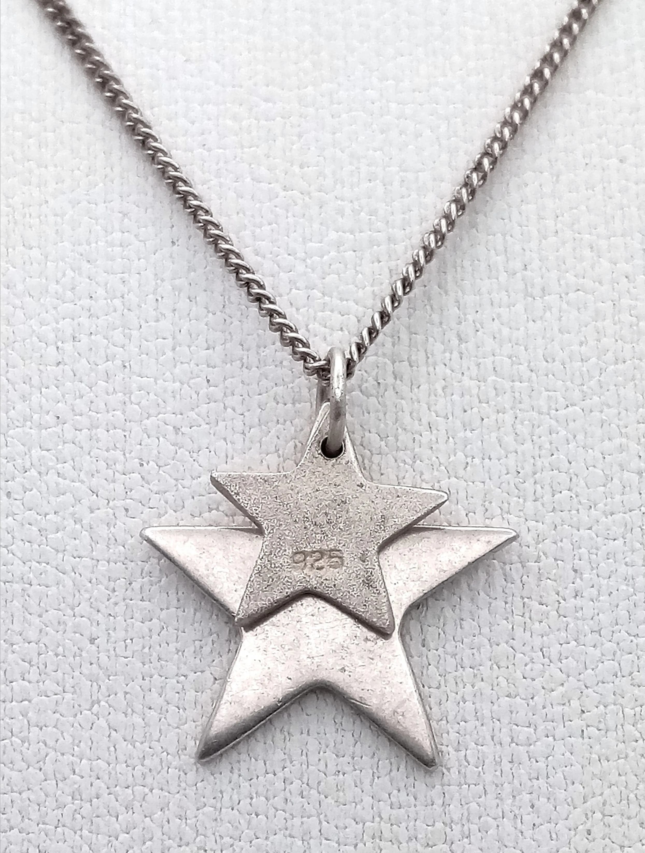 A Pretty 925 Sterling Silver Double Star Pendant Necklace - 44cm Length. Features two polished star pendants on a fine silver chain. The larger star measures 1.5cm x 1.5cm and the smaller star measures 1cm x 1cm. Gross weight 2.59 grams.