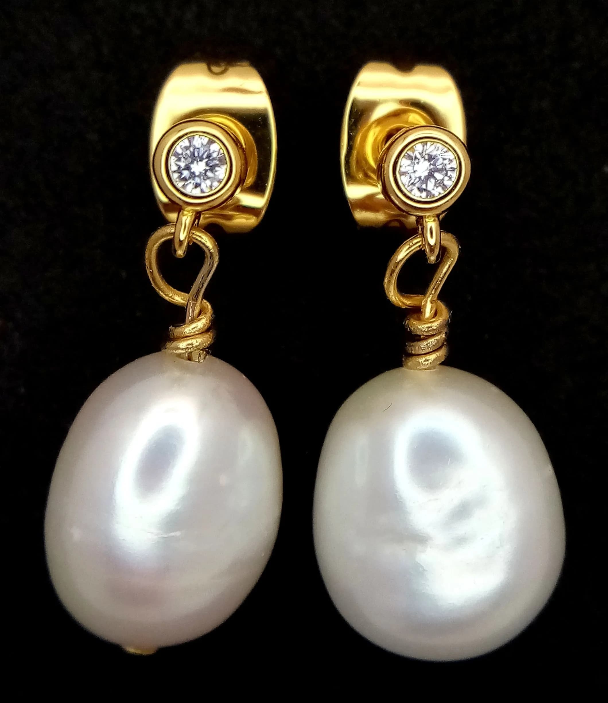 An Elegance Pair of Gold Tone Freshwater Pearl and CZ Stone Drop Earrings. Features irregular freshwater pearl drops suspended from bezel set CZ stones, with butterfly fittings. Each earring measures 1.7cm drop. The pearls measure approximately 8.6mm.