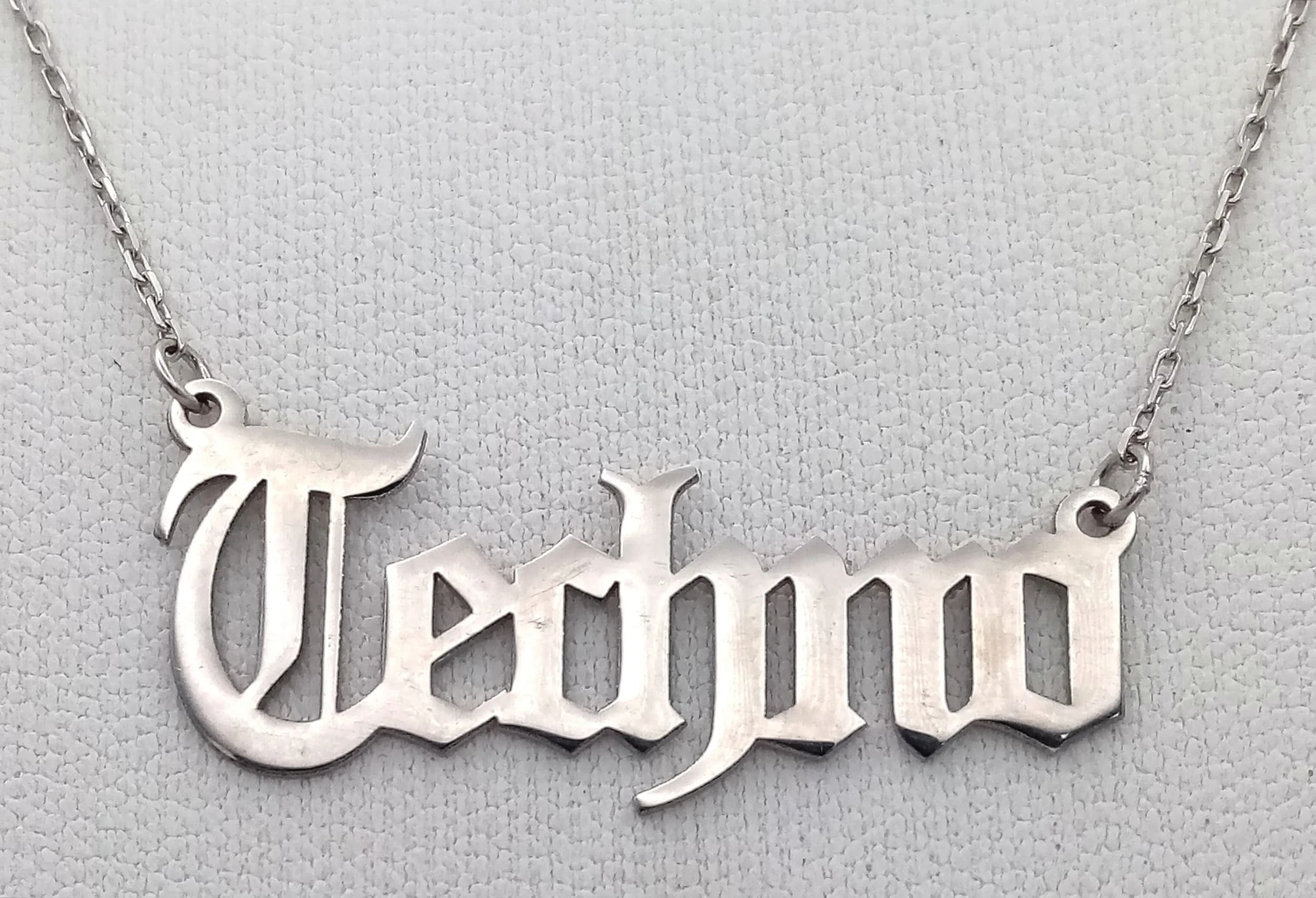 A Stylish "TEDMO" 925 Sterling Silver Name Pendant Necklace - 45cm Length. Features a gothic-style "TEDMO" name pendant on a fine silver chain with an extension section. The pendant measures 3cm x 1cm. Gross weight 2.42 grams.