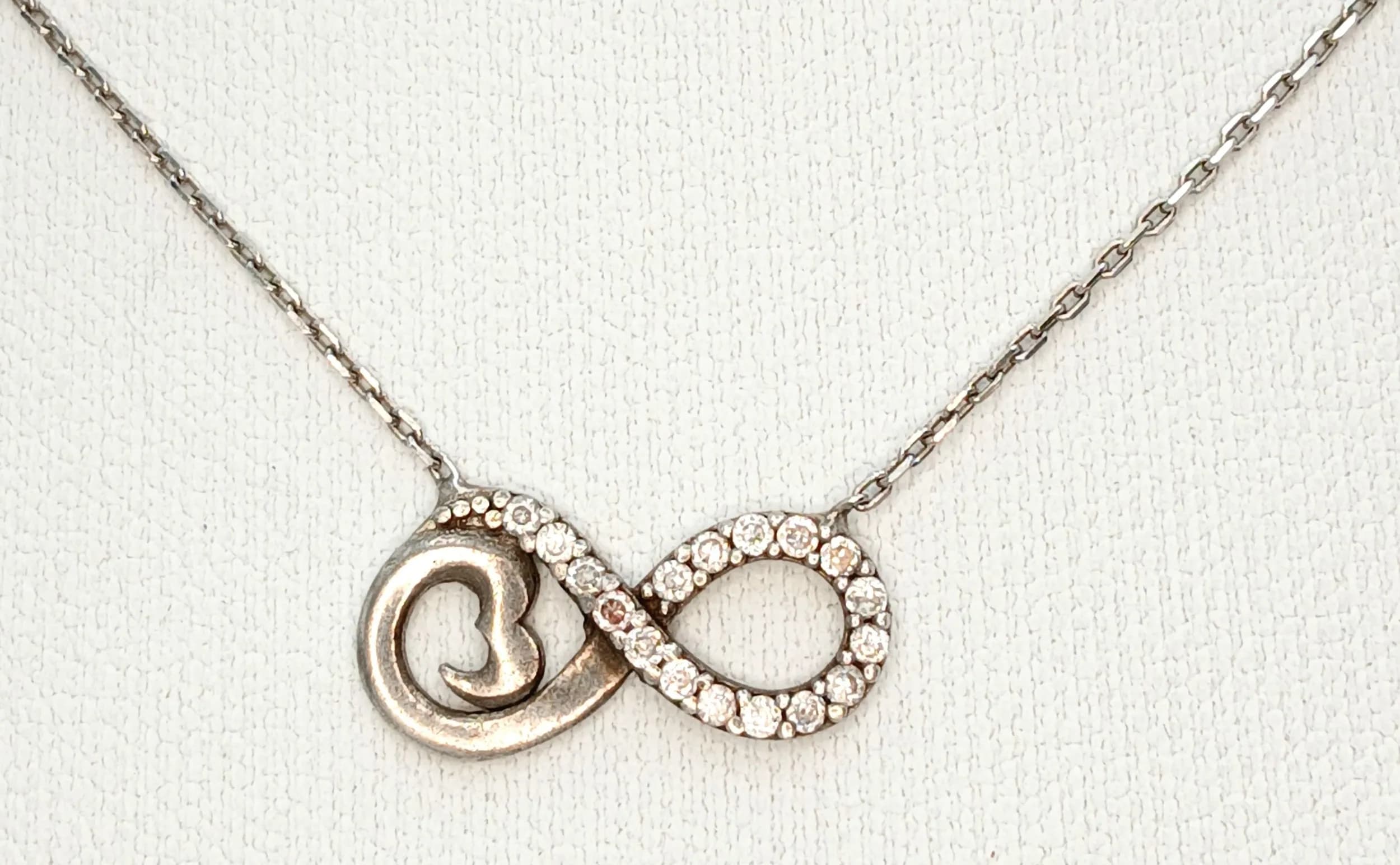 A Lovely 925 Sterling Silver Eternity Pendant Necklace-42cm Length Chain. The Pendant features an Interlocking Circle Design with one Plain Polished Circle and one White Stone Set Eternity Circle, measuring 1.5cm x 0.8cm. The Necklace has a gross weight of 1.79 grams.