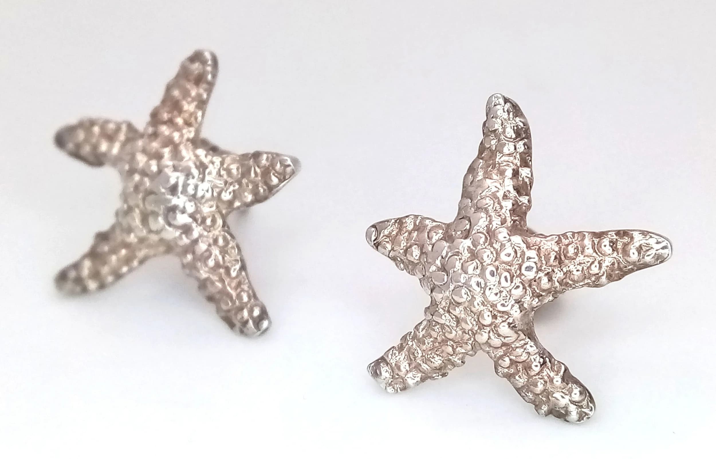 A Pretty Pair of 925 Sterling Silver Starfish Stud Earrings. Features textured starfish designs with post and butterfly fittings. Each earring measures 1.3cm x 1.5cm. Gross weight 1.79 grams.