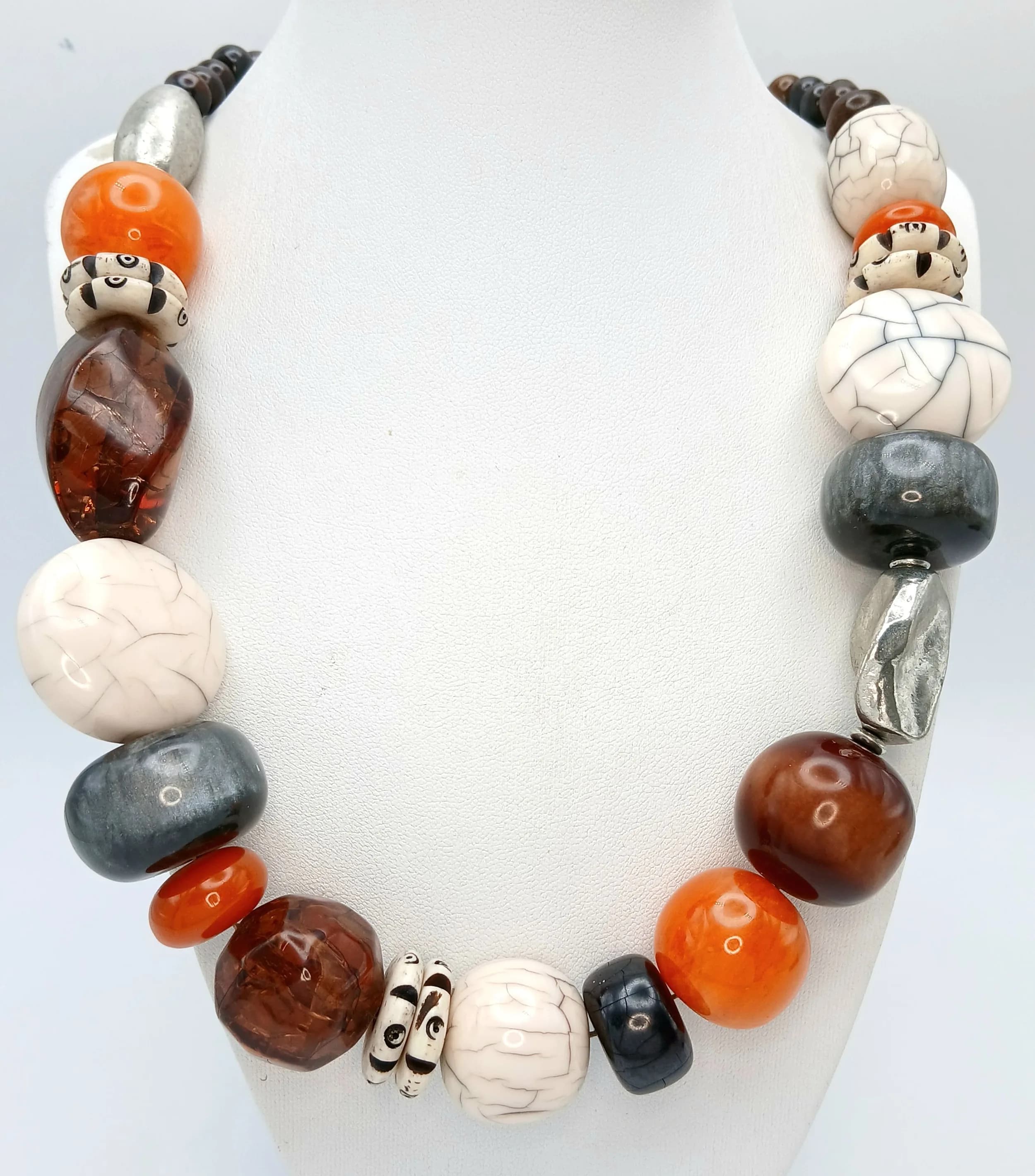 A Striking Mixed Bead Necklace - 56cm Length. Features graduated resin and ceramic-style beads in white, brown, orange, grey and silver tones, with smaller dark brown beads towards the fastening.
