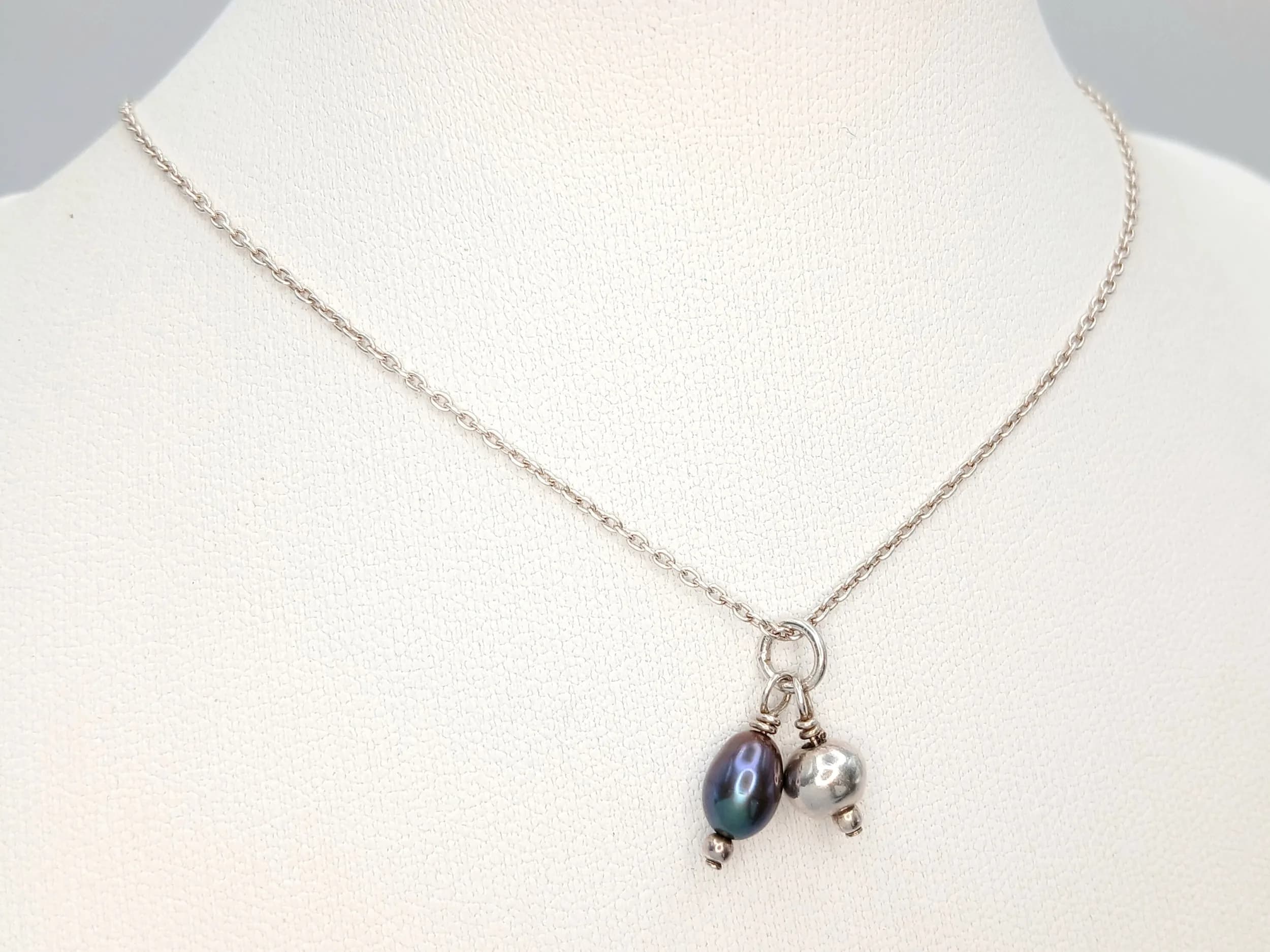 A Charming 925 Sterling Silver Necklace with Freshwater Pearl and Silver Ball Charms -38cm Length Chain. The Pendant features a Freshwater Pearl Drop with a Silver Bead Accent and measures 1cm Drop. The Necklace has a gross weight of 2.87 grams.