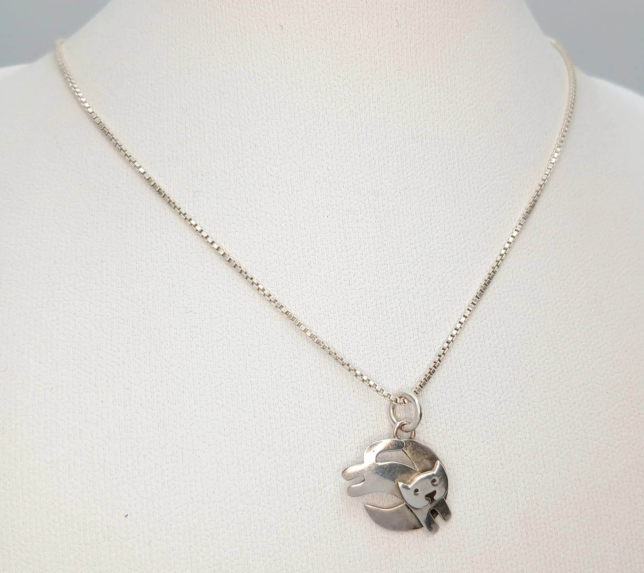 A Stunning Italian 925 Sterling Silver Cat and Moon Pendant Necklace. The pendant features a cat and moon-shaped decorative silver design. The necklace measures 44cm length. The pendant measures 1.5cm drop. Gross weight of necklace is 4 grams.